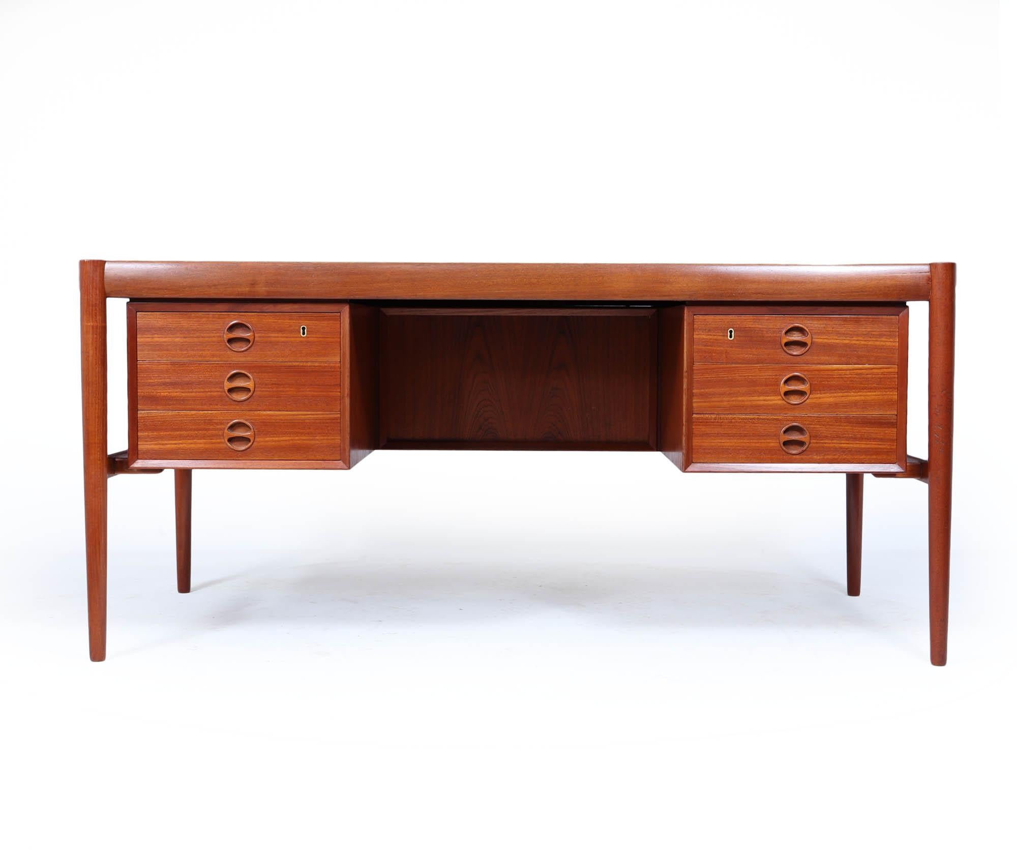 A striking mid-century Danish executive desk, crafted in richly toned teak with minimalist lines and impeccable proportions. Designed in the 1960s, this piece combines form and function with two banks of drawers—each with signature circular recessed
