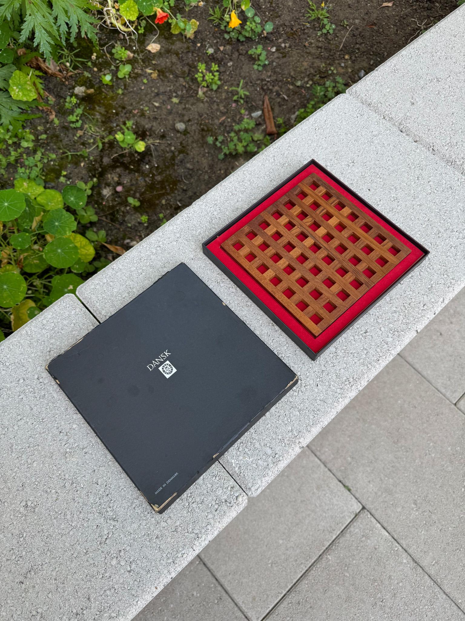 Dessous de plat en treillis de teck de Jens Quistgaard avec boîte d'origine pour Dansk, Danemark, c.1965.  Le dessous de plat est estampillé Danmark. 

Le dessous de plat mesure 6,5