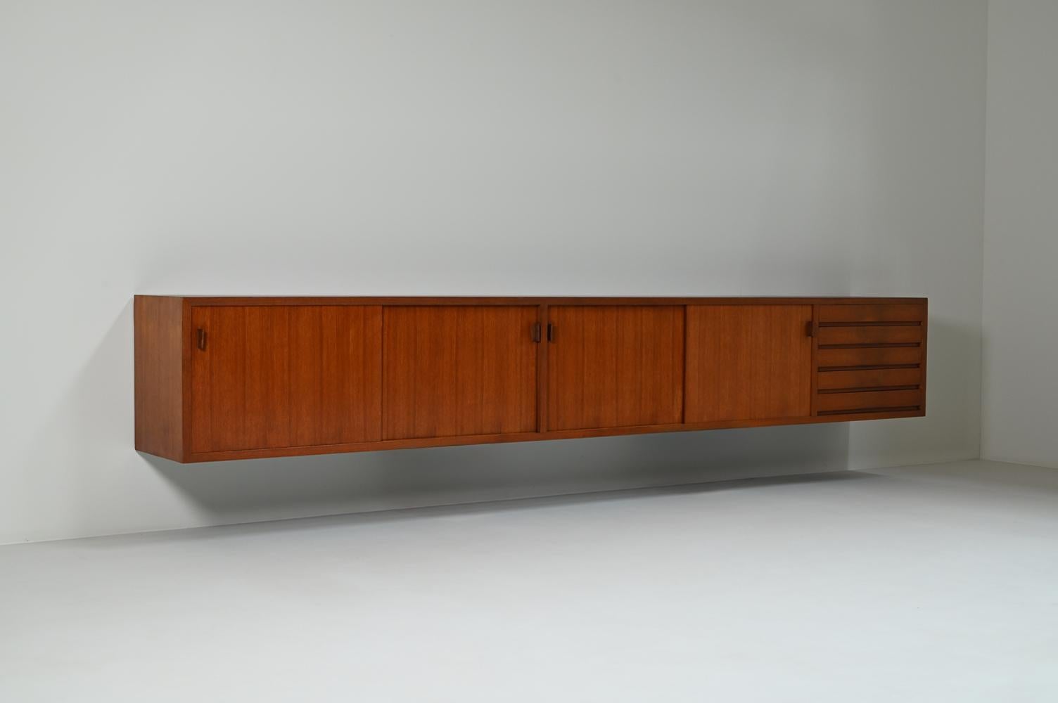 Large teak floating sideboard, 1960s Germany. This sideboard is a beautiful example of mid-century modern design. Clean, functional design with minimal ornamentation. The sideboard is mounted on the wall, giving it a light, modern feel. It features