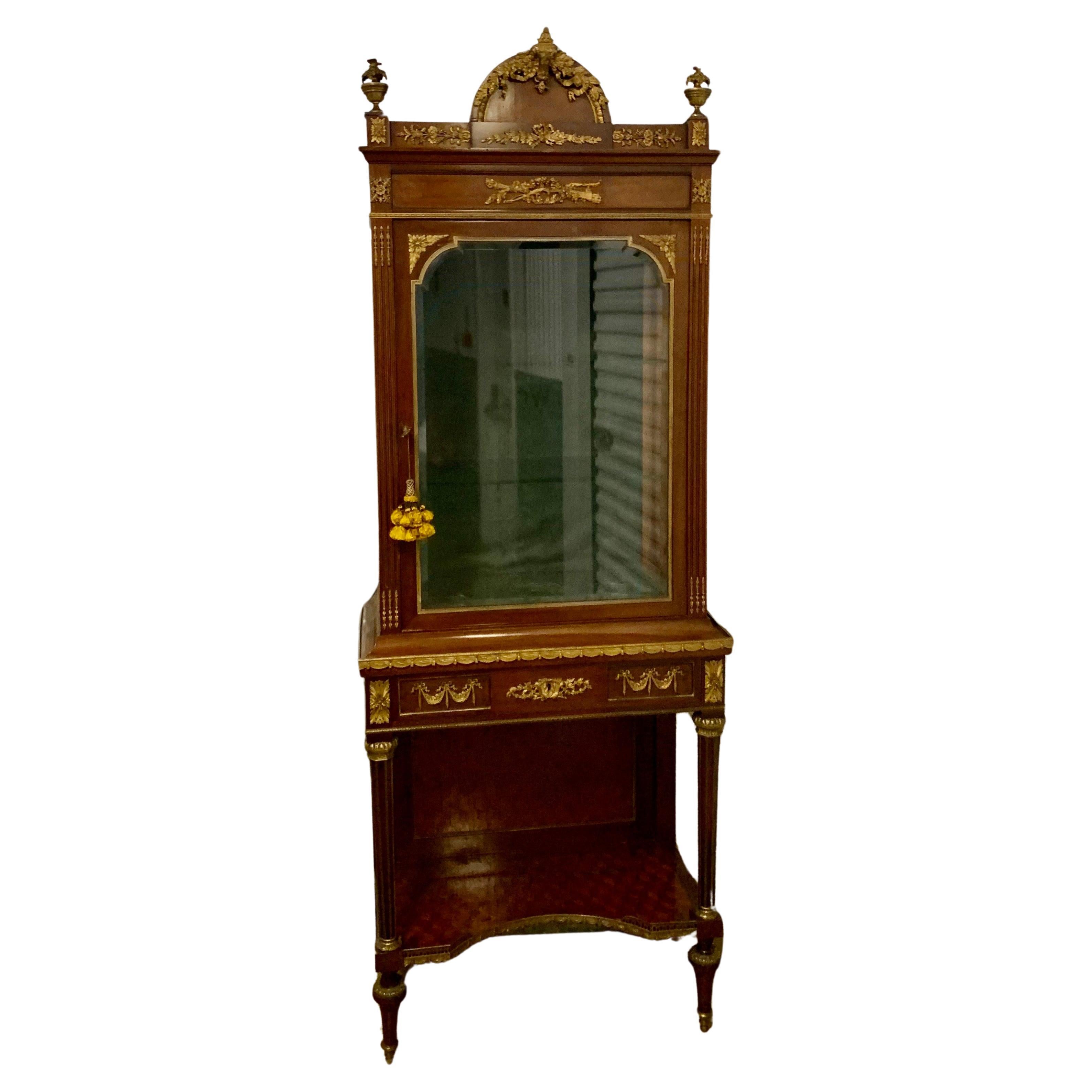 A fine quality piece with superbly cast ormolu mounts against dark mahogany wood.
Of rectangular form, the vitrine with oak leaf cresting, above a conforming frieze centred with a bow and quiver and central glass door, on fluted tapering legs