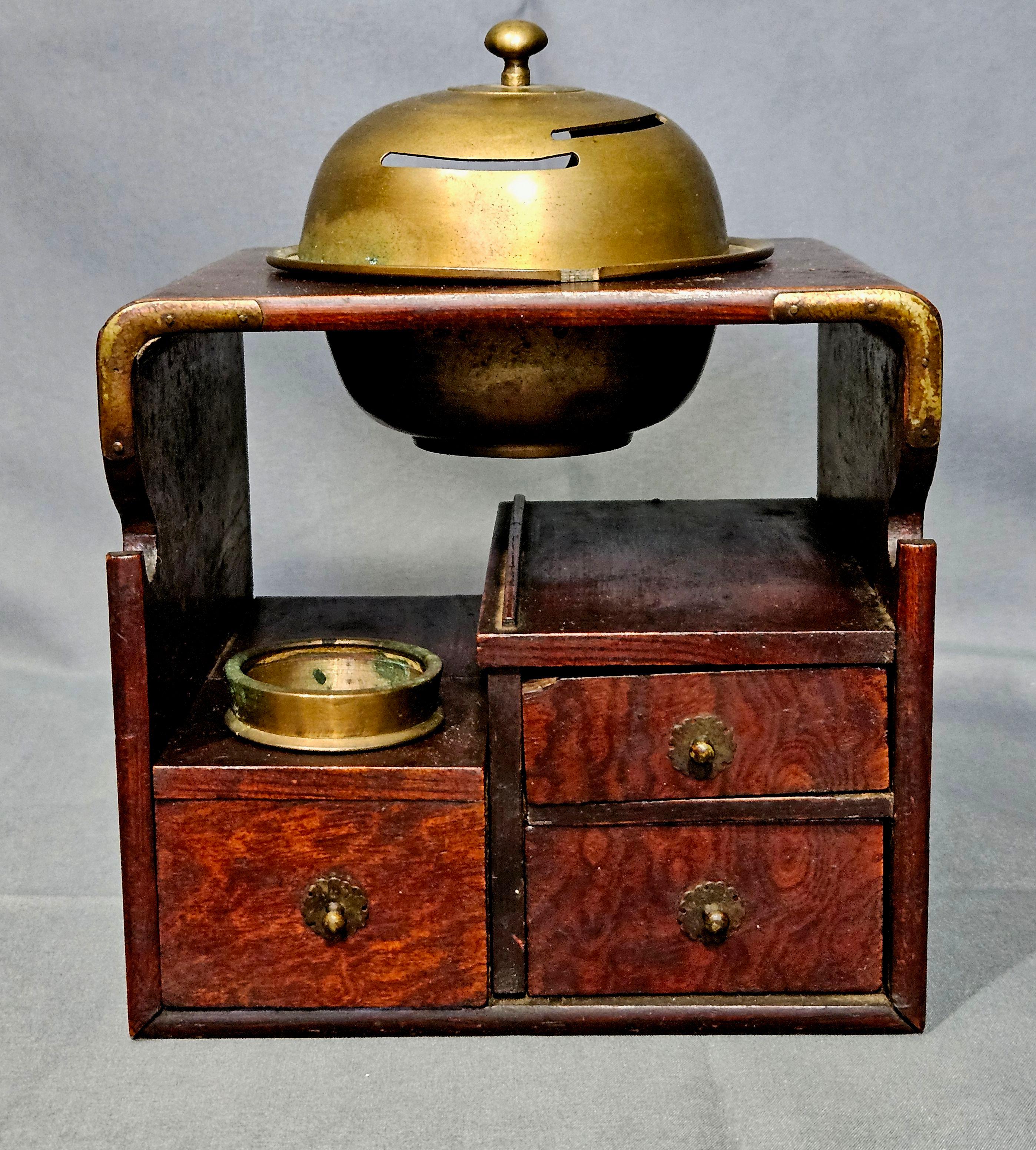 JAPANESE ELMWOOD TABAKO-BON
19th c. Wooden Tobacco Tray, used to store tobacco and smoking items, the top with domed brass hibachi or hi-ire with removable vented lid for lighting a pipe; lower section with front cut-out for holding a smoking pipe,