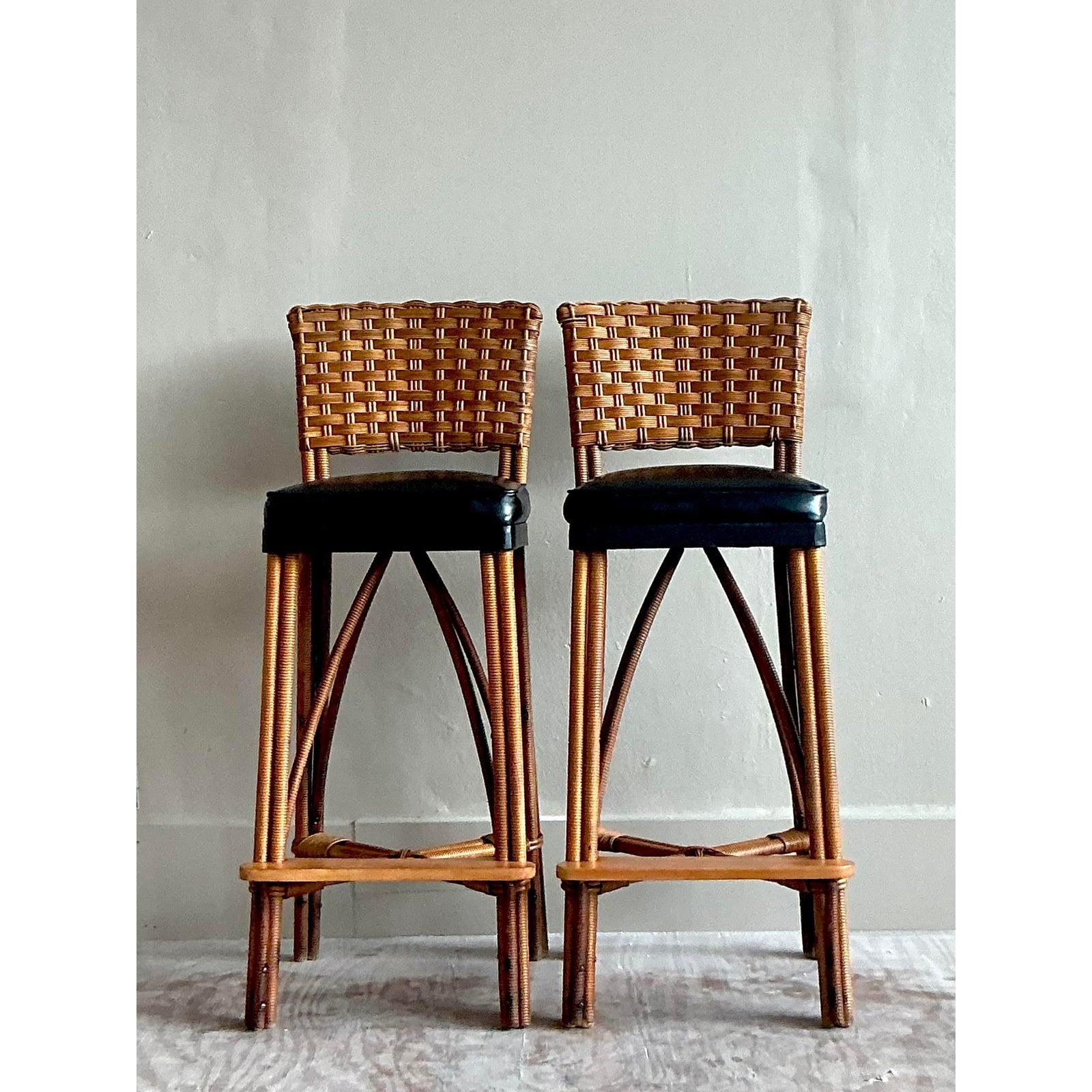 Channel the breezy sophistication of a tropical resort with this stunning pair of vintage woven rattan bar stools. Expertly handcrafted, these stools feature intricately woven wicker backrests and meticulously wrapped rattan legs, showcasing a rich