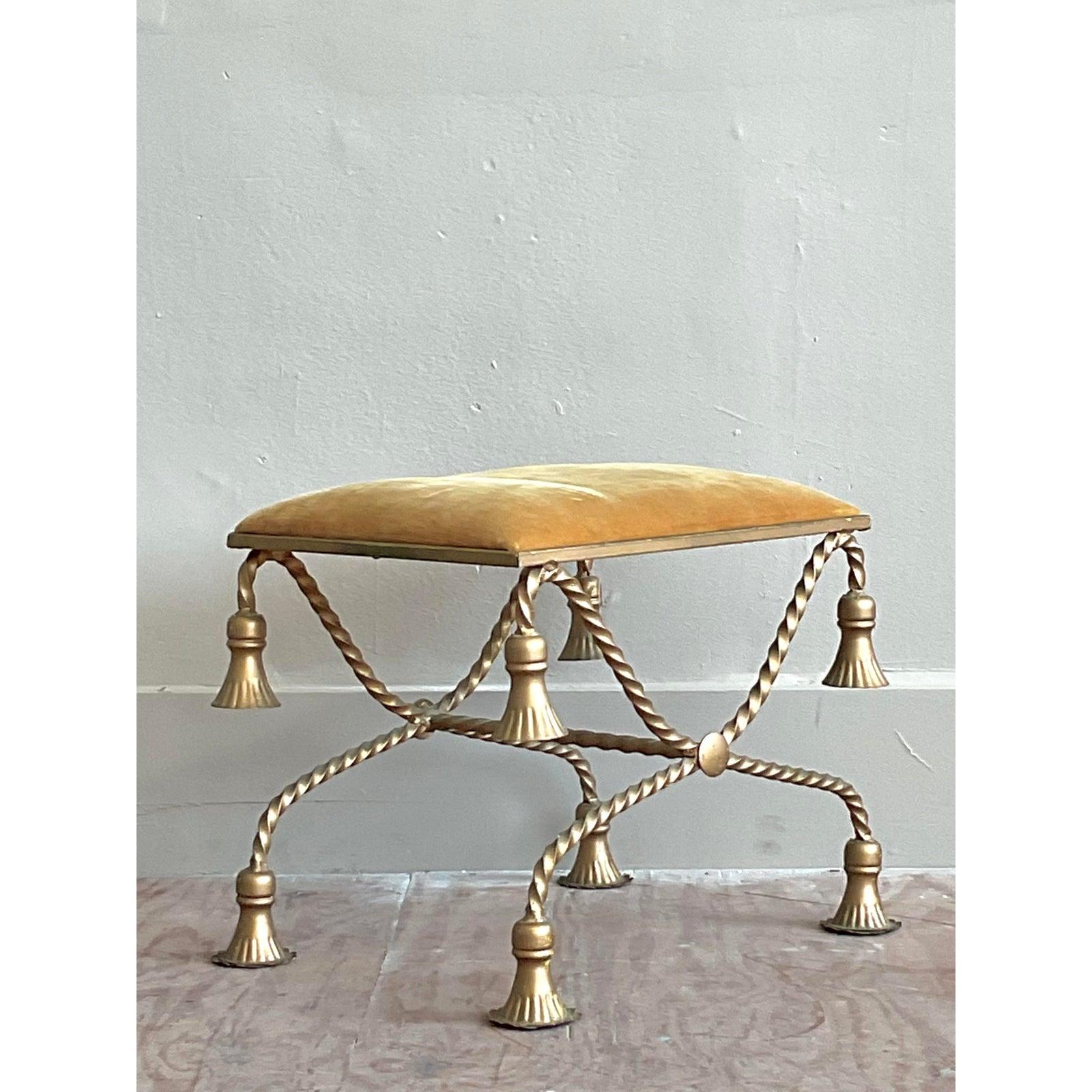Desvela un toque de exquisito glamour Hollywood Regency con este encantador taburete de tocador Vintage Twisted Tassel, una encantadora pieza de acento rebosante de carácter único. Este elegante banco presenta una base en forma de X de intrincado