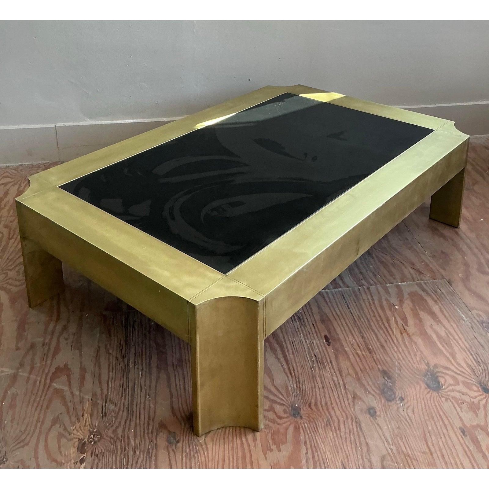 Commanding attention with its sleek lines and luminous finish, this Vintage Notched Brass Coffee Table is an exceptional example of refined Mid-Century design with a distinct Hollywood Regency flair. Its substantial brass frame, featuring unique