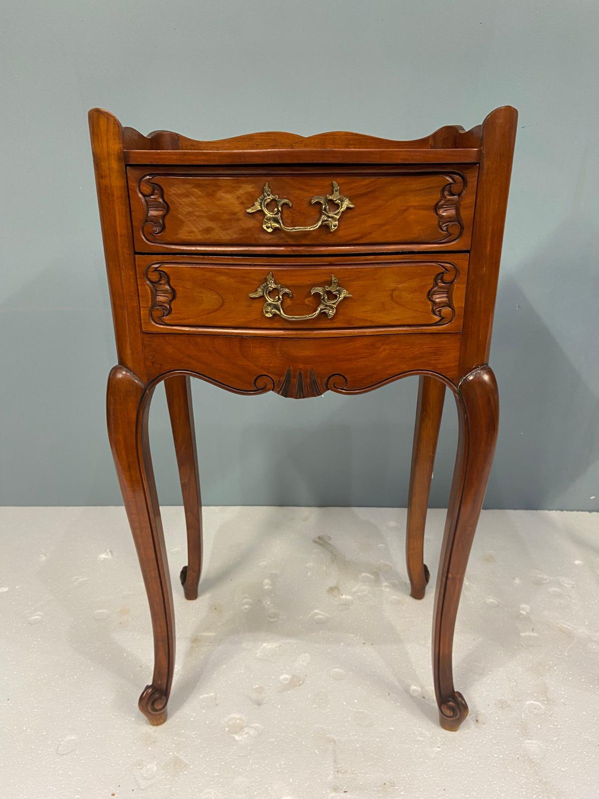 Stai visualizzando una raffinata coppia di comodini o armadi francesi in legno di noce
I tavoli presentano eleganti frontali a serpentina e grembiuli smerlati, tipici dell'influenza rococò, che conferiscono loro una silhouette morbida e