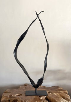 Gran escultura de madera de suar, con acabado quemado sobre un soporte de metal negro, estilo orgánico moderno