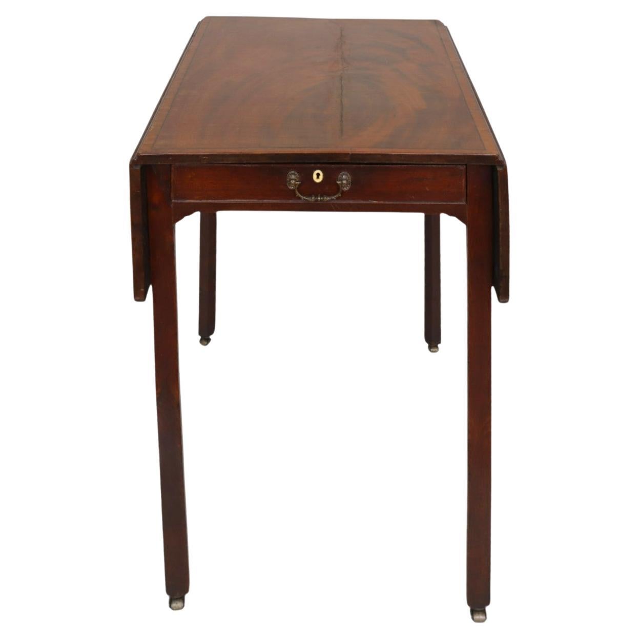 A George III period Pembroke table circa 1760. Made of mahogany, the tabletop is decorated with burlwood veneers. A single hand dovetailed drawer opens with a brass bail handle. The other side is decorated with a bail handle to give the look of a
