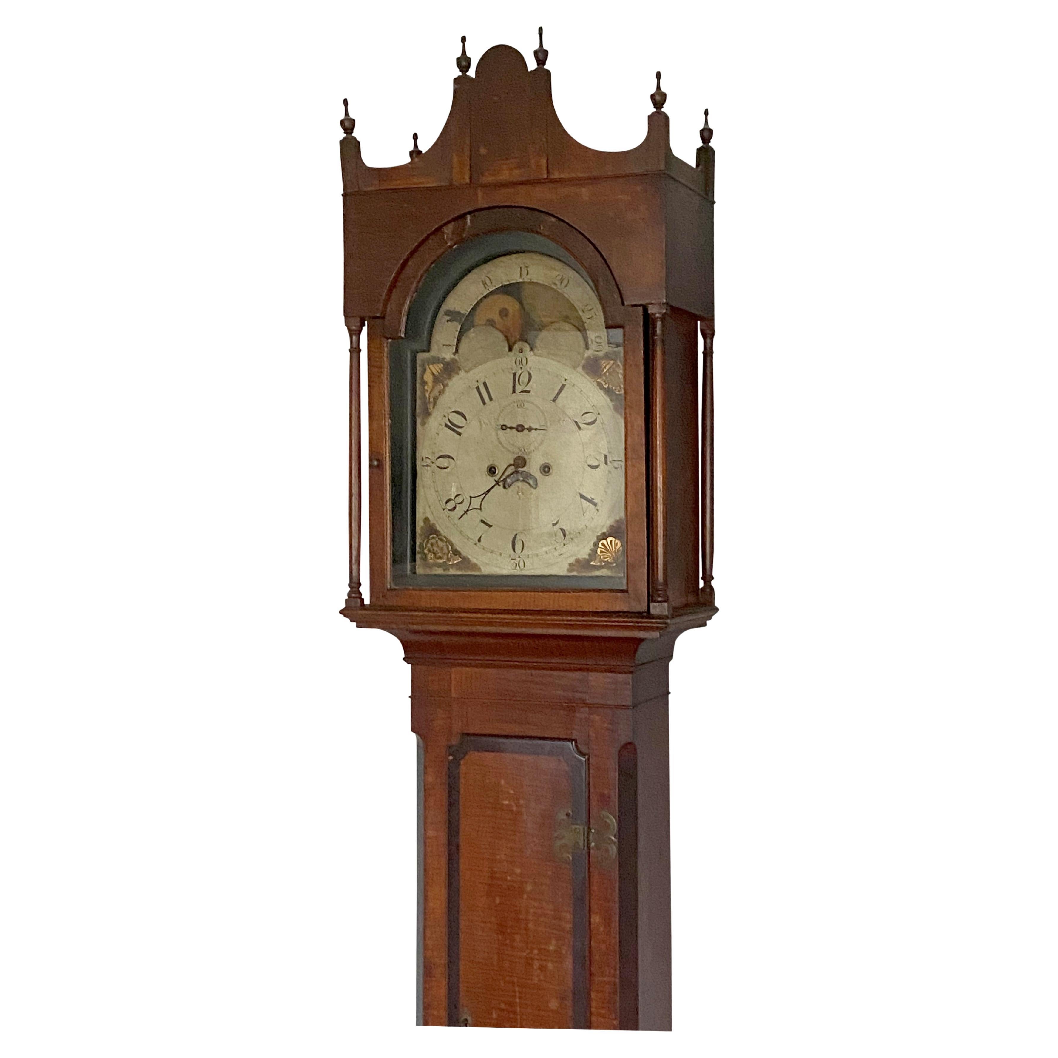 Distinctive federal curly maple tall case clock with mahogany banding, Pennsylvania, circa 1810. IN a remarkable state of preservation and with slender 'french' feet and original urn shaped finials. The 8 day two train movement has original dial and
