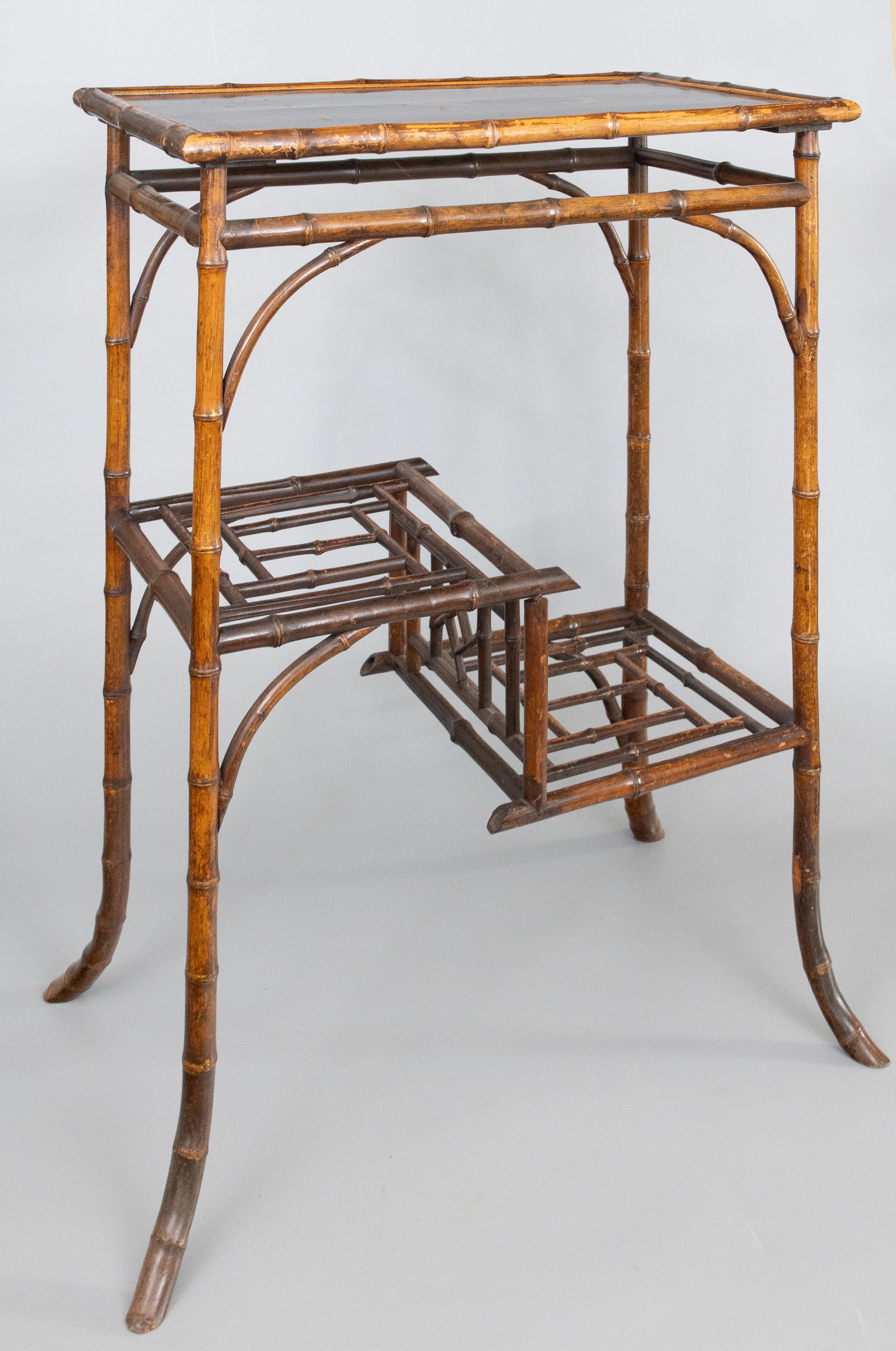 A superb antique English bamboo rectangular tiered side table with lacquered top, circa 1880. This fine table has the lovely original black lacquer top with hand painted chinoiserie design, lower tiered shelves with ornamental open bamboo fretwork,