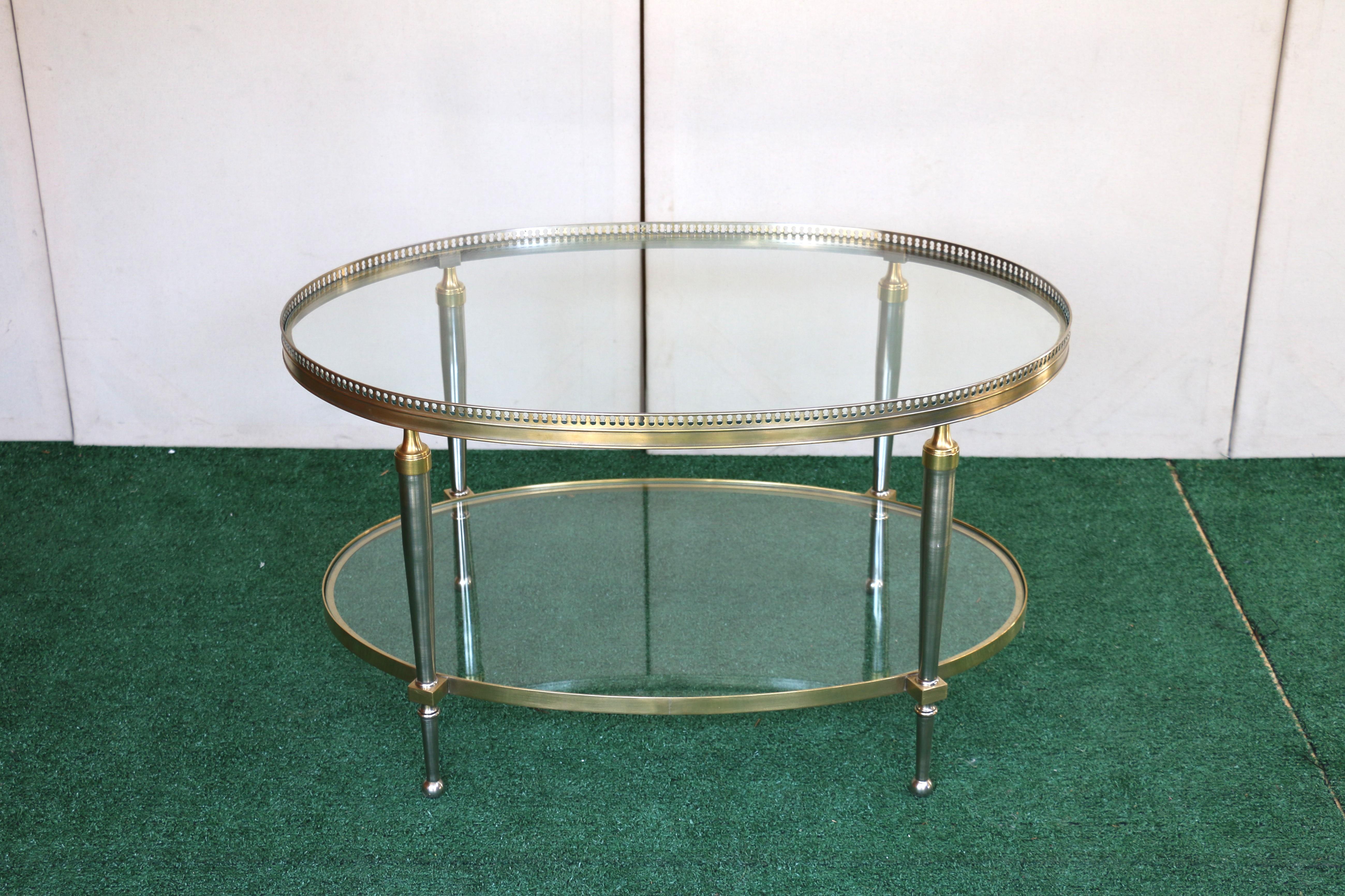 Tavolino da caffè di forma ovale della fine del XX secolo di Trouvailles Inc. di Watertown, Ma. Realizzato in acciaio e ottone con inserti in vetro. Presenta una galleria traforata e gambe affusolate che sfociano in piedi a sfera. Buone condizioni.