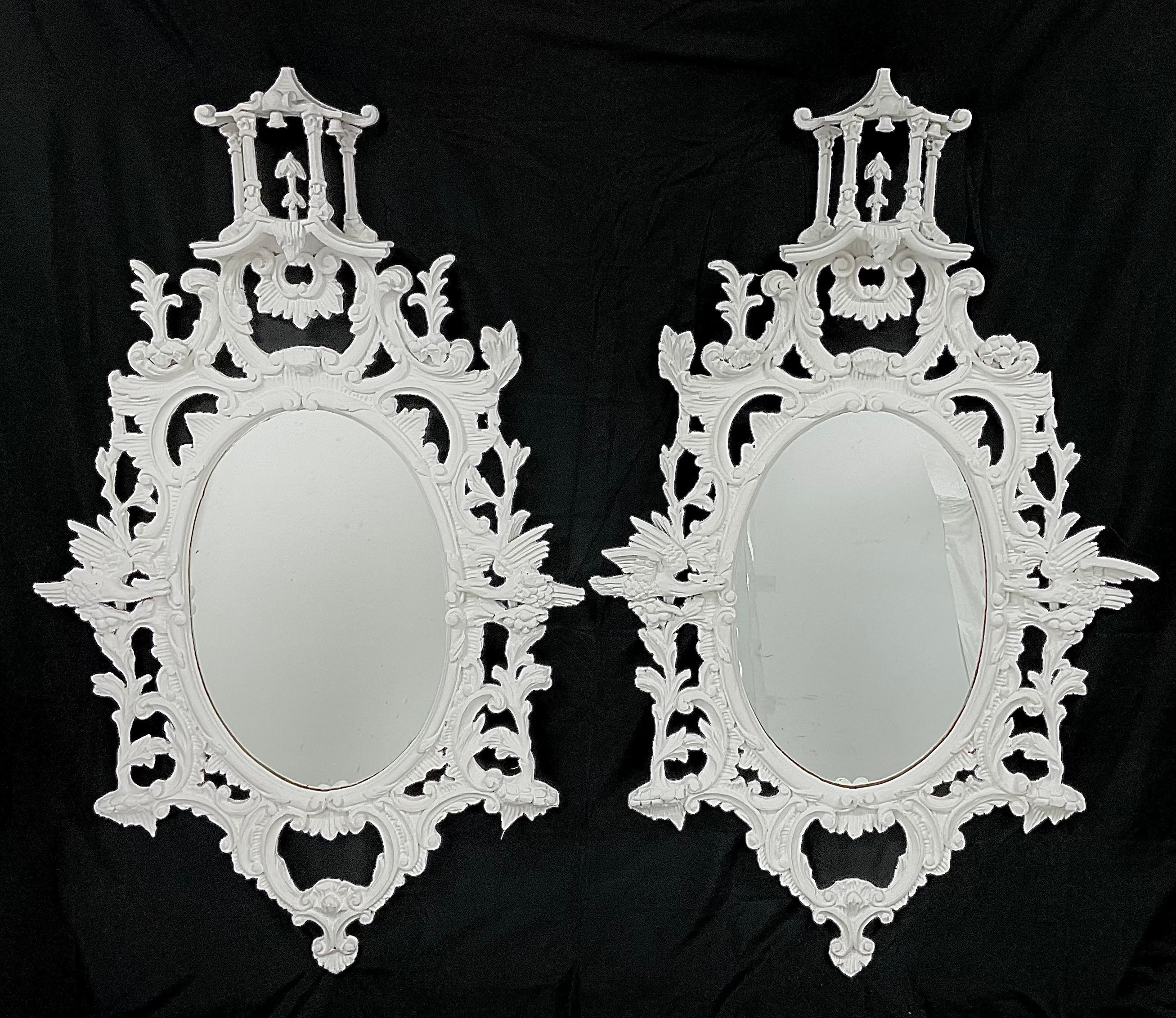 A pair of large late 19th century white painted mirrors in the Chinese Chippendale style Constructed in carved wood, the oval mirror plates housed within elaborate frames with foliate tree branches, cascading icicles, with carved Ho-Ho birds perched