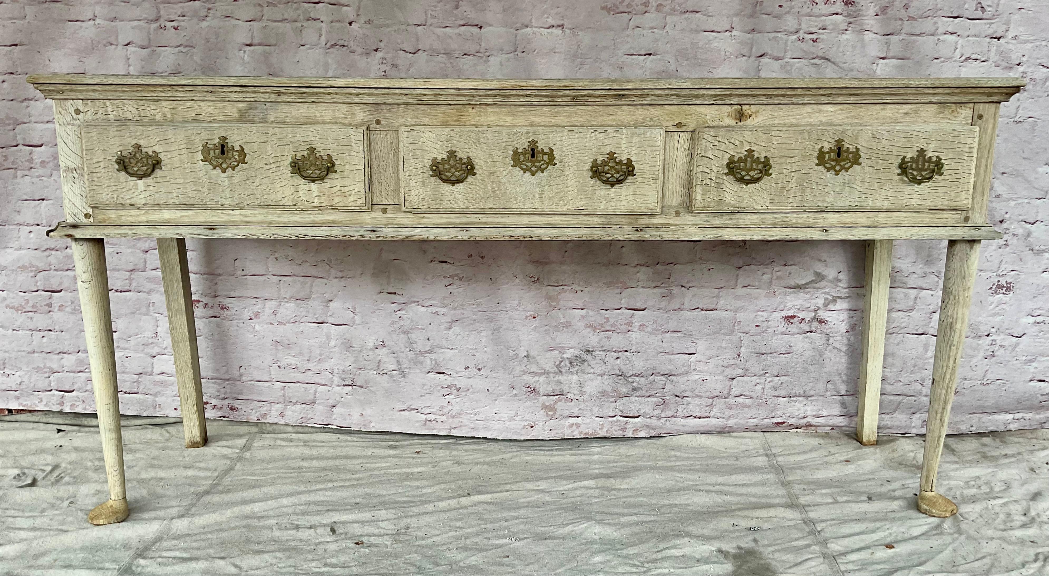 An 18th century George III English bleached oak dresser / sideboard / console, a classic piece of furniture that embodies the craftsmanship and style of its time. Dresser features three spacious drawers with brass hardware and cabriole legs