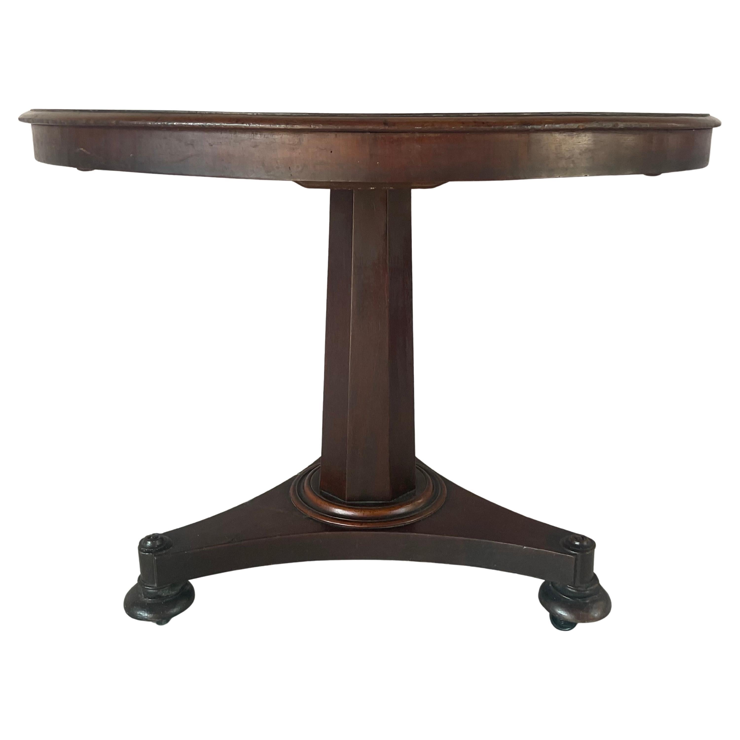 Early 19th Century English Tilt-Top Table. Table is crafted in rich mahogany and features a well-figured top supported on a bold turn pedestal rising from a tripartite base with stylized bun feet and casters --hallmarks of the regency design. Piece