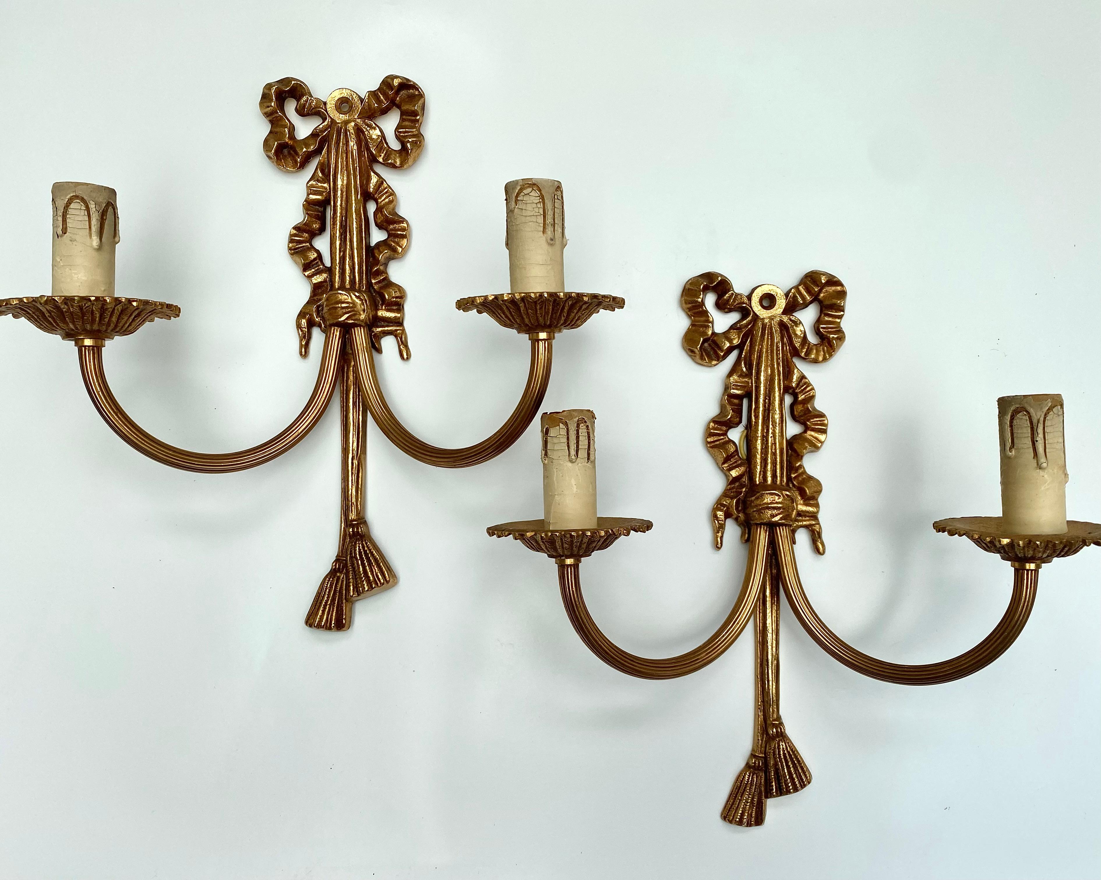 Pareja de apliques franceses vintage.

Estas asombrosas piezas están fabricadas en bronce dorado, con intrincados detalles que recuerdan al estilo Luis XVI, o quizá al movimiento neoclásico en general.

Su elegante diseño presenta delicados lazos y