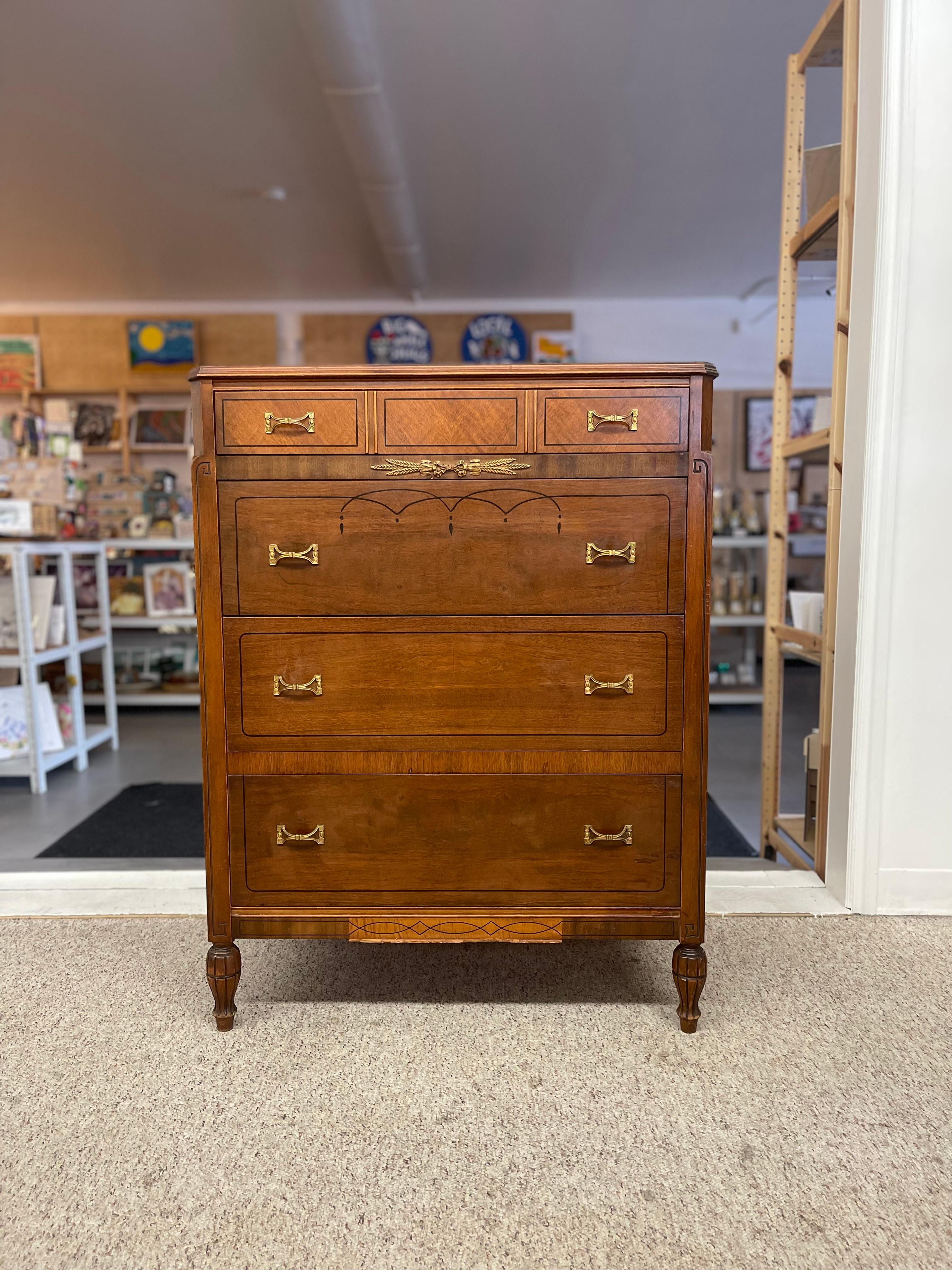 Neoclassical style tall chest of drawers, circa early 20th century Constructed possibly from mahogany, with decorative inlay, including black linework and a stylized swag motif between the first and second drawer.
Features four graduated