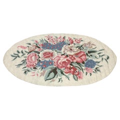 Tappeto ovale con motivi floreali a punto catenella, realizzato a mano in lana, nei colori rosa e blu, prodotto in India.