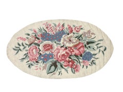 Tappeto ovale con motivi floreali a punto catenella, realizzato a mano in lana, nei colori rosa e blu, prodotto in India.