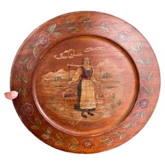 Plato decorativo de madera noruego de época, pintado a mano, que representa a una mujer del pueblo.