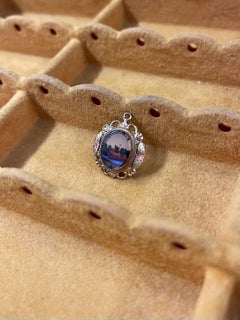 Colgante vintage en tono dorado, en miniatura, con forma de paisaje y un marco de filigrana muy elaborado.