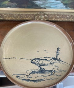 Piatto in ceramica da studio della metà del secolo con scena costiera raffigurante un faro, dipinta a mano.