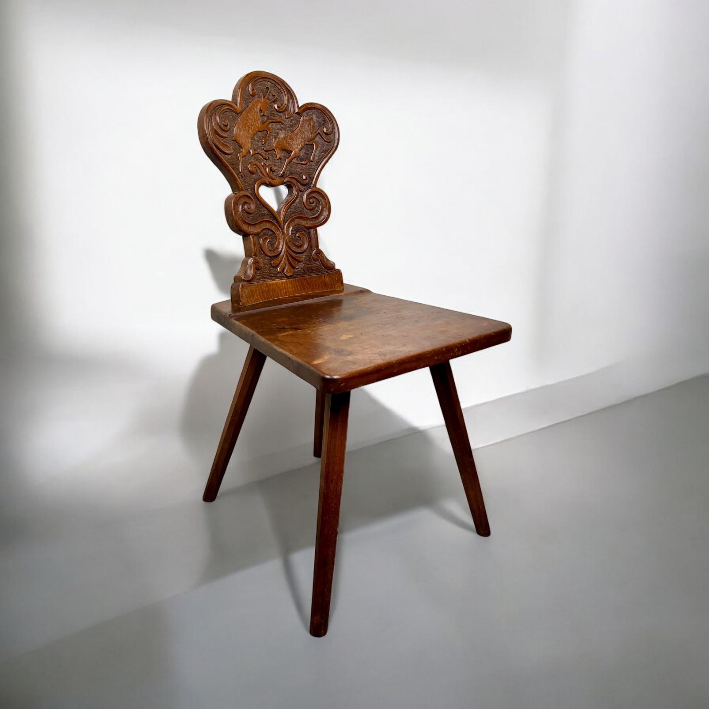 Délicieuse chaise ESCABELLE d'art populaire alpin suisse.

Cette charmante antiquité présente un dossier magnifiquement sculpté, orné d'une paire de chamois des Alpes au-dessus d'un cœur stylisé central, encadré par des rinceaux de