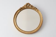 Miroir ovale en bois doré, orné d'un blason floral de style rococo, milieu du XXe siècle