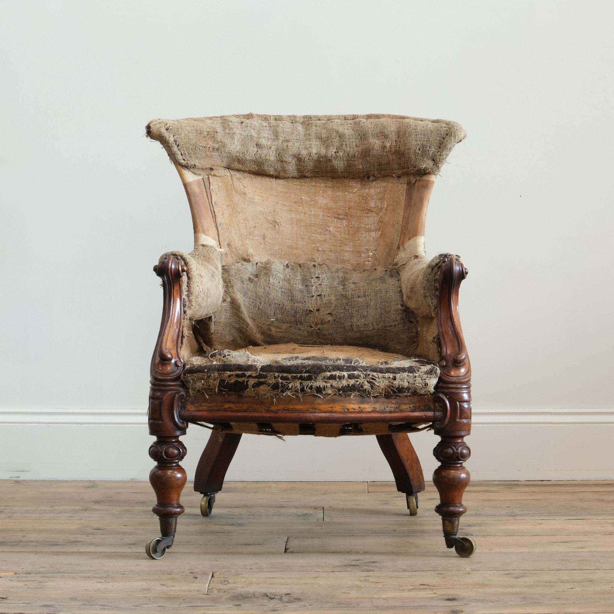 Un elegante sillón de casa de campo de mediados del siglo XIX. Levantada sobre patas delanteras de nogal torneadas y talladas, con patas traseras ensanchadas y todas con ruedas de latón. La silla tiene una forma especialmente bonita, con los frentes