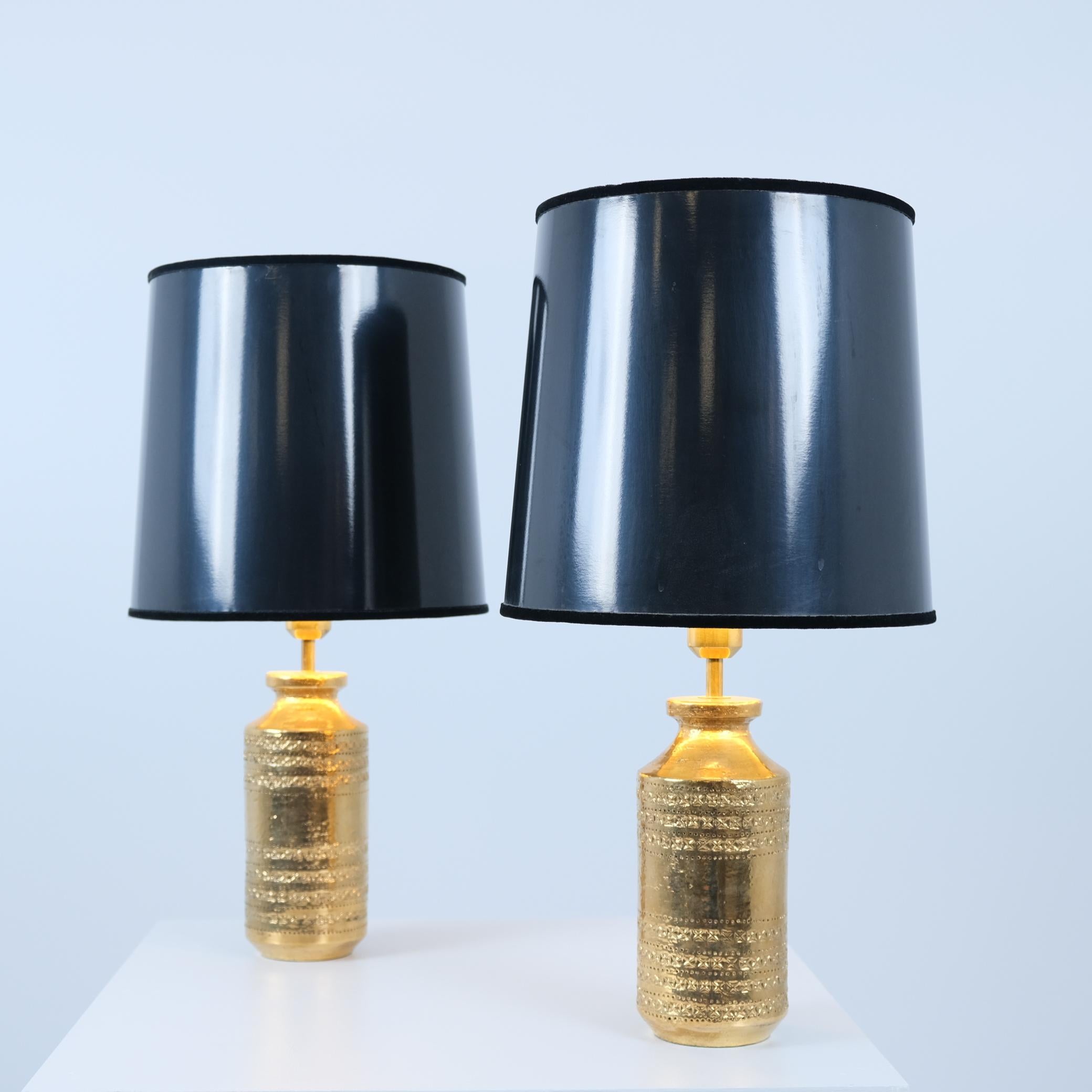 Une paire de lampes de table en céramique faites à la main, ornées d'une glaçure dorée lustrée et de détails en laiton raffinés, associées à d'élégants abat-jours en tissu noir et or. Un travail d'orfèvre réalisé par Bitossi pour le célèbre