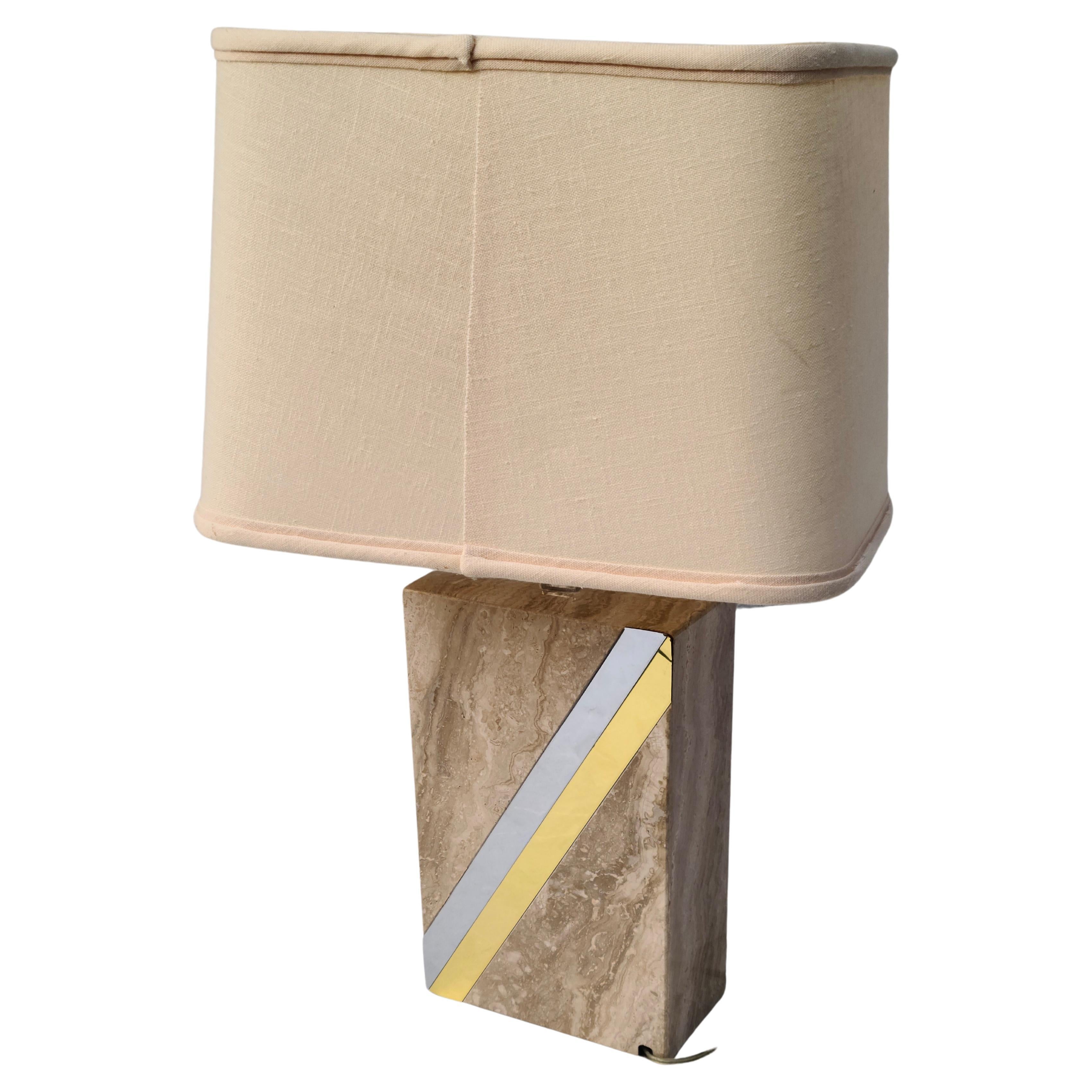 Table Lamp marked Raymor. 
Travertine base with brass and chrome applique.
Shade has some damage from use: Heat of bulb, etc. 