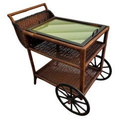 Un carrello da tè/bar in vimini con vassoio di servizio, ripiano centrale e inferiore e cestino per le bottiglie