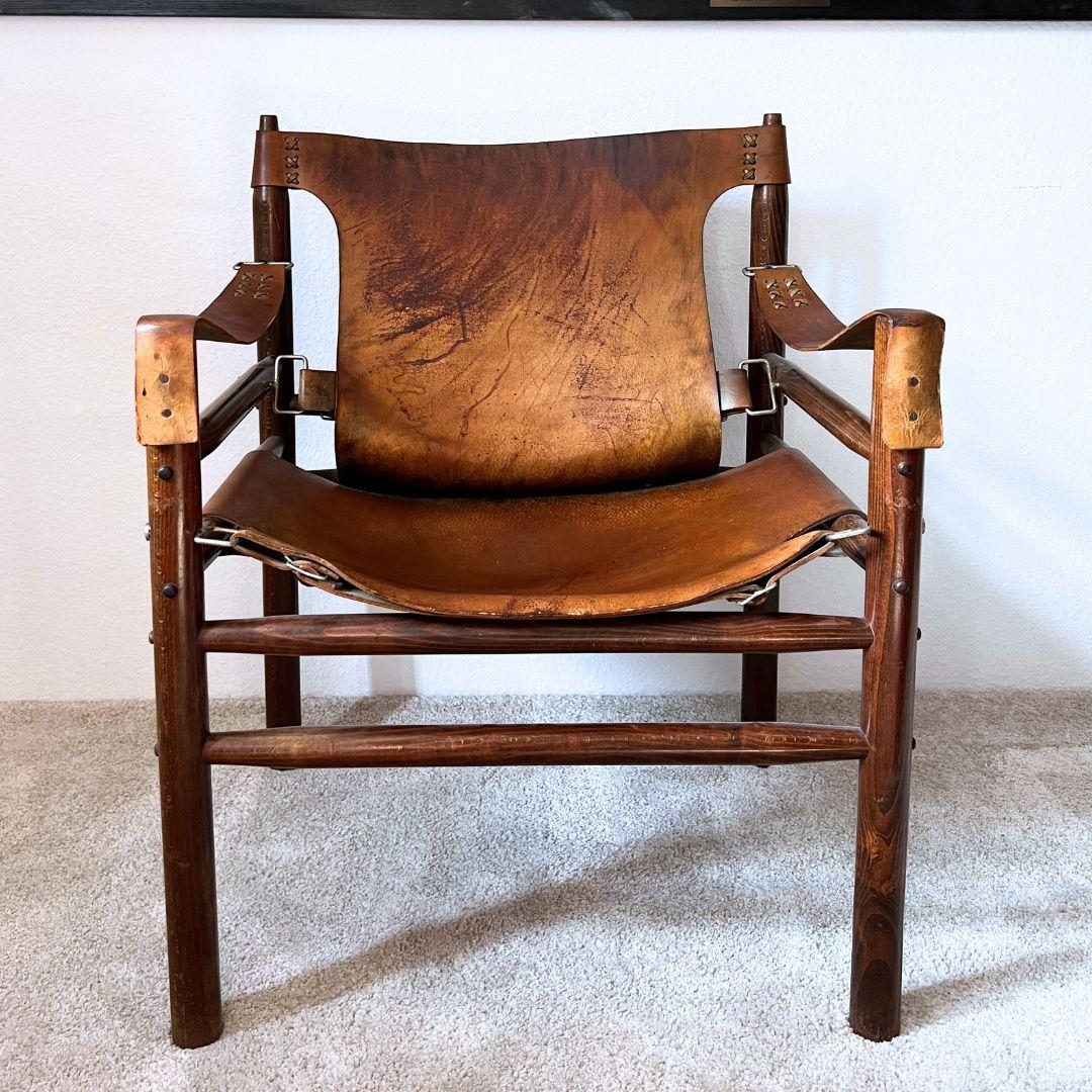 Questa sedia rilassata in stile safari degli anni '70 ha un look fresco e classico. La pelle di bufalo è invecchiata molto bene e ha acquisito una ricca patina nel corso degli anni. Il telaio in rovere massiccio è ancora robusto e in ottima