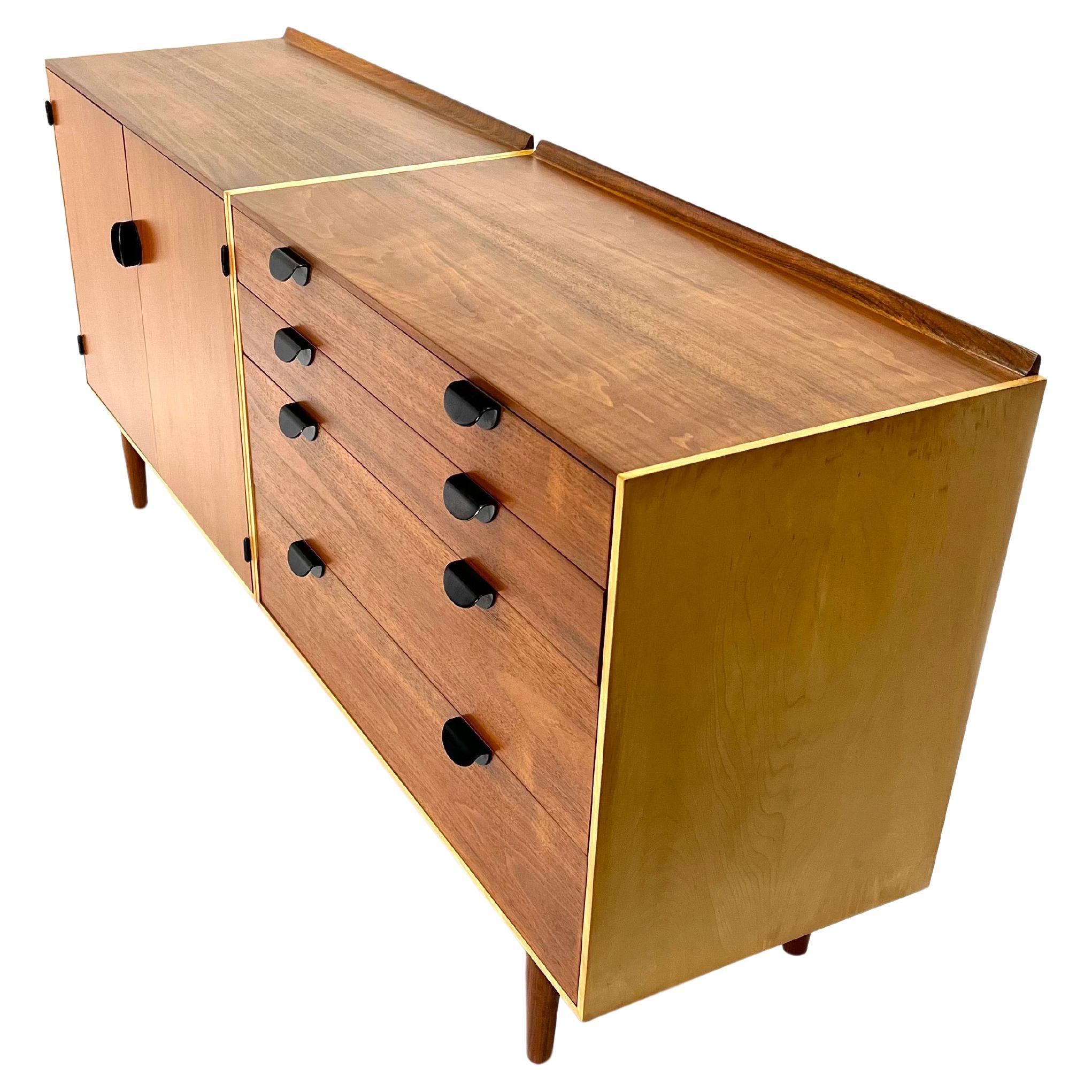 This incredible teak and maple credenza is designed by Finn Juhl and is fully restored. This is a beautiful example of his work. The teak case is topped with a raised back-rail, four stacked drawers with black enamel brass pulls raised on tapered