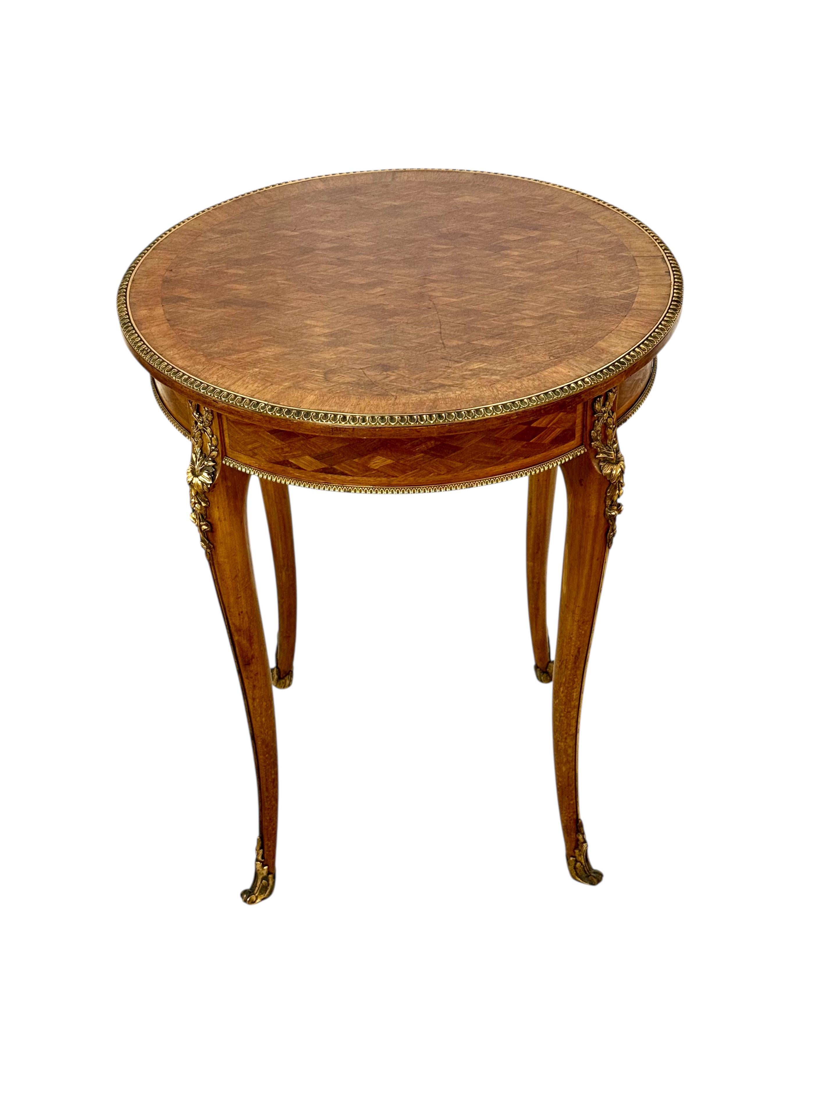 Questo squisito guéridon rotondo è stato realizzato in Francia nel XIX secolo, ispirandosi alle linee aggraziate e ai ricchi ornamenti dello stile Luigi XV. Progettato come elegante tavolino d'appoggio o d'accento, presenta un piano intarsiato con