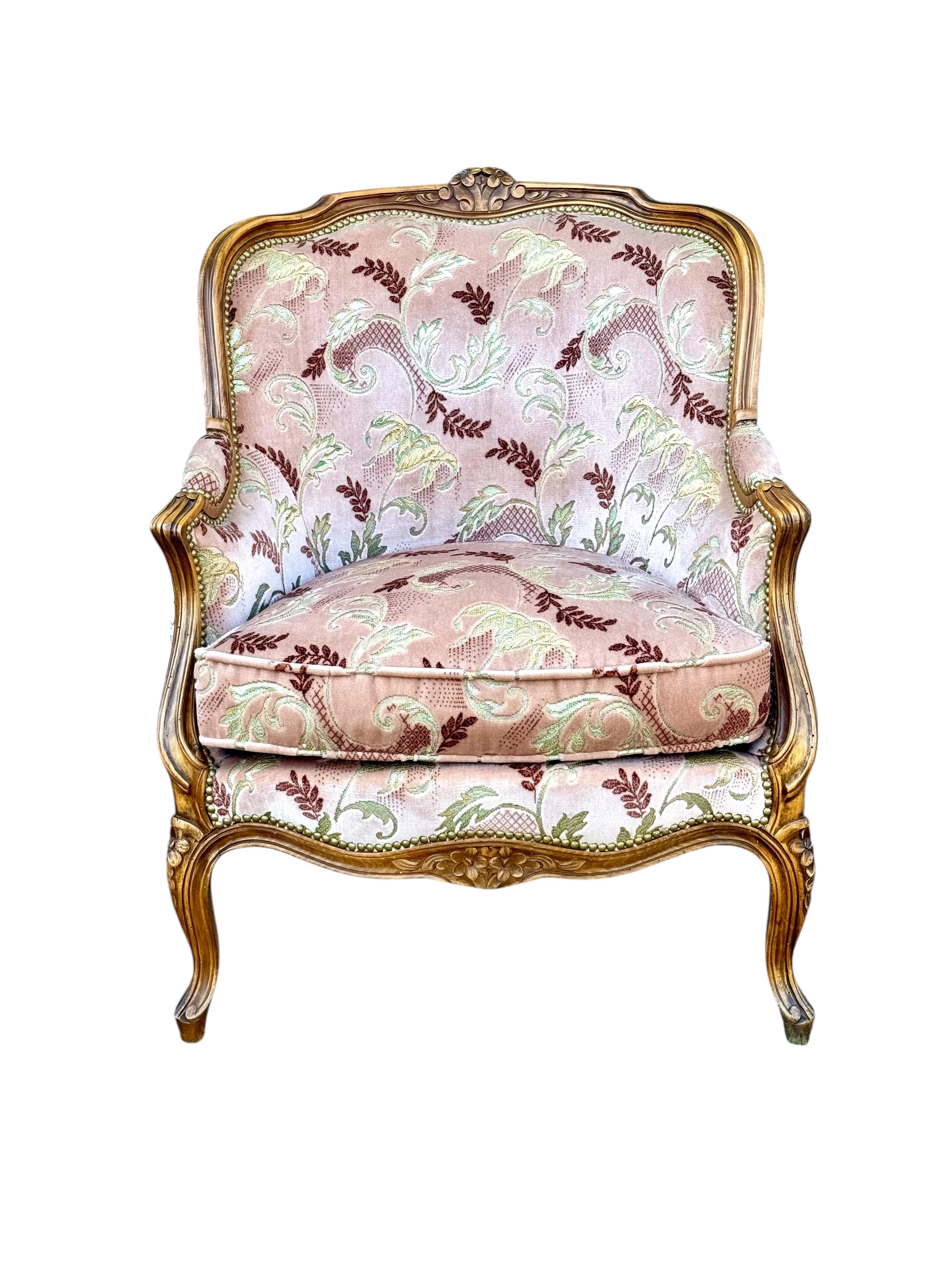 Cet exquis fauteuil bergère français a été fabriqué à la fin du XIXe siècle dans le style Louis XV, mettant en valeur l'élégance intemporelle des arts décoratifs français. Fabriqué en noyer français massif, le cadre est finement sculpté de motifs