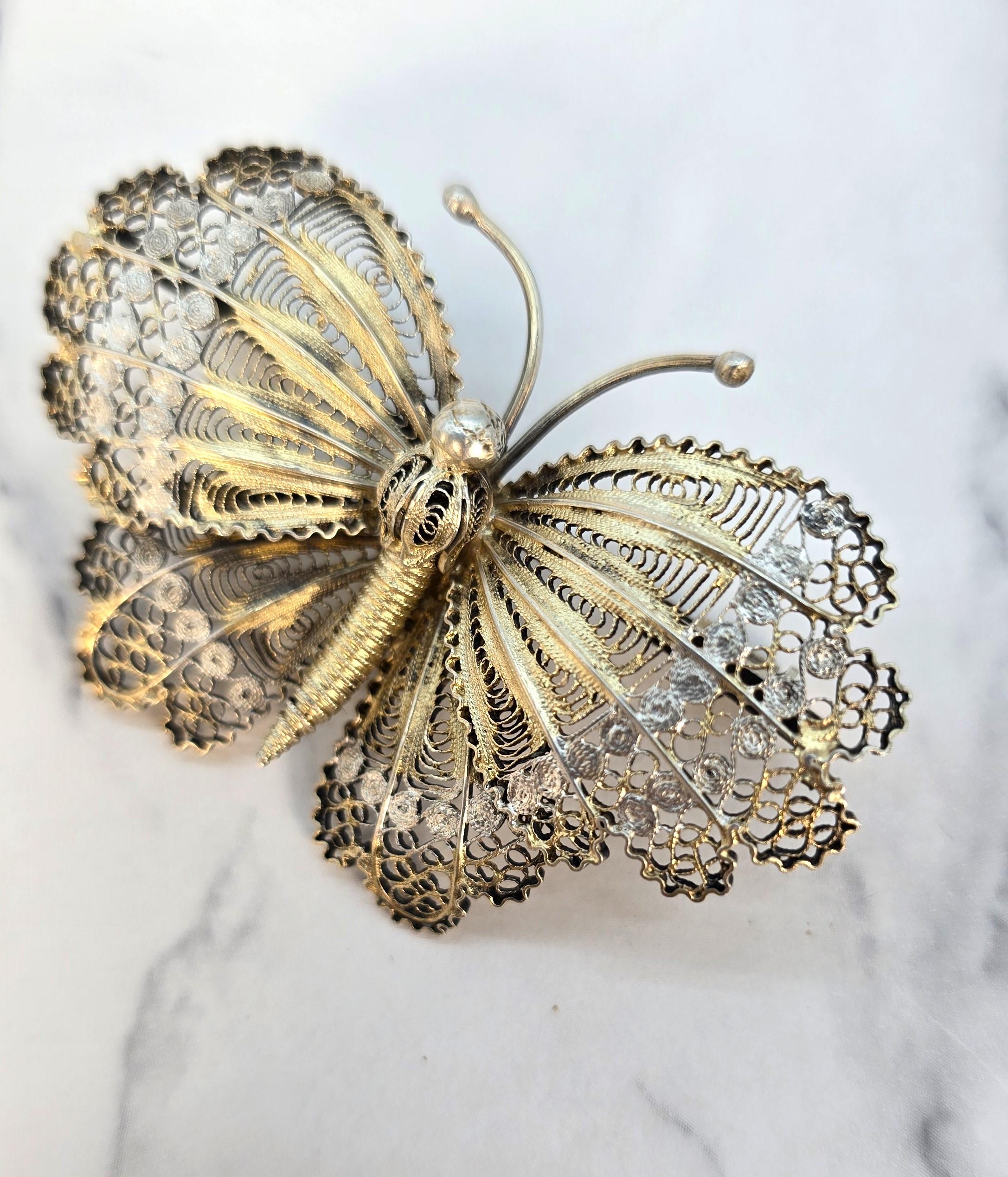 Ce très bel exemple provient très probablement de Malte ou d'Italie, où ce travail raffiné était populaire, et date d'environ 1930.

Elle a la forme d'un grand papillon à deux ailes, réalisé à la main en fil d'argent fin, qui a été façonné et soudé