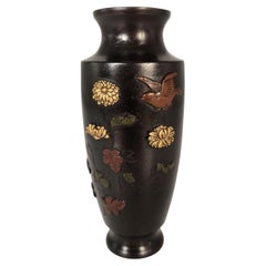 A Japanese Meiji period bronze vase decorated in high relief foliage and a bird