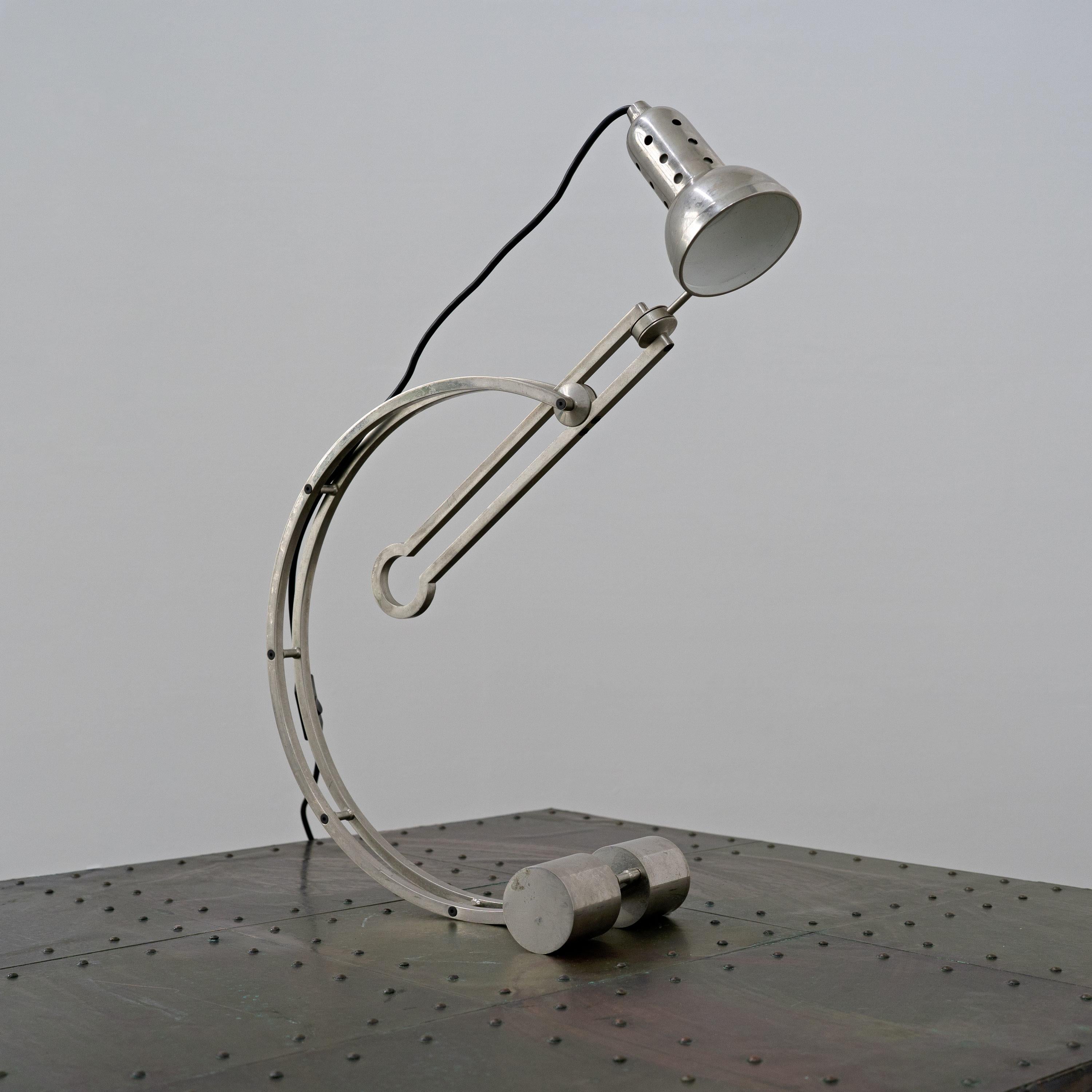 Lampe de table nickelée conçue par Charles Martin en 1928 et produite par Woka à Vienne dans la seconde moitié du XXe siècle. Il se caractérise par un arc de cercle  cadre ancré sur deux pieds cylindriques avec une tête de lampe perforée qui