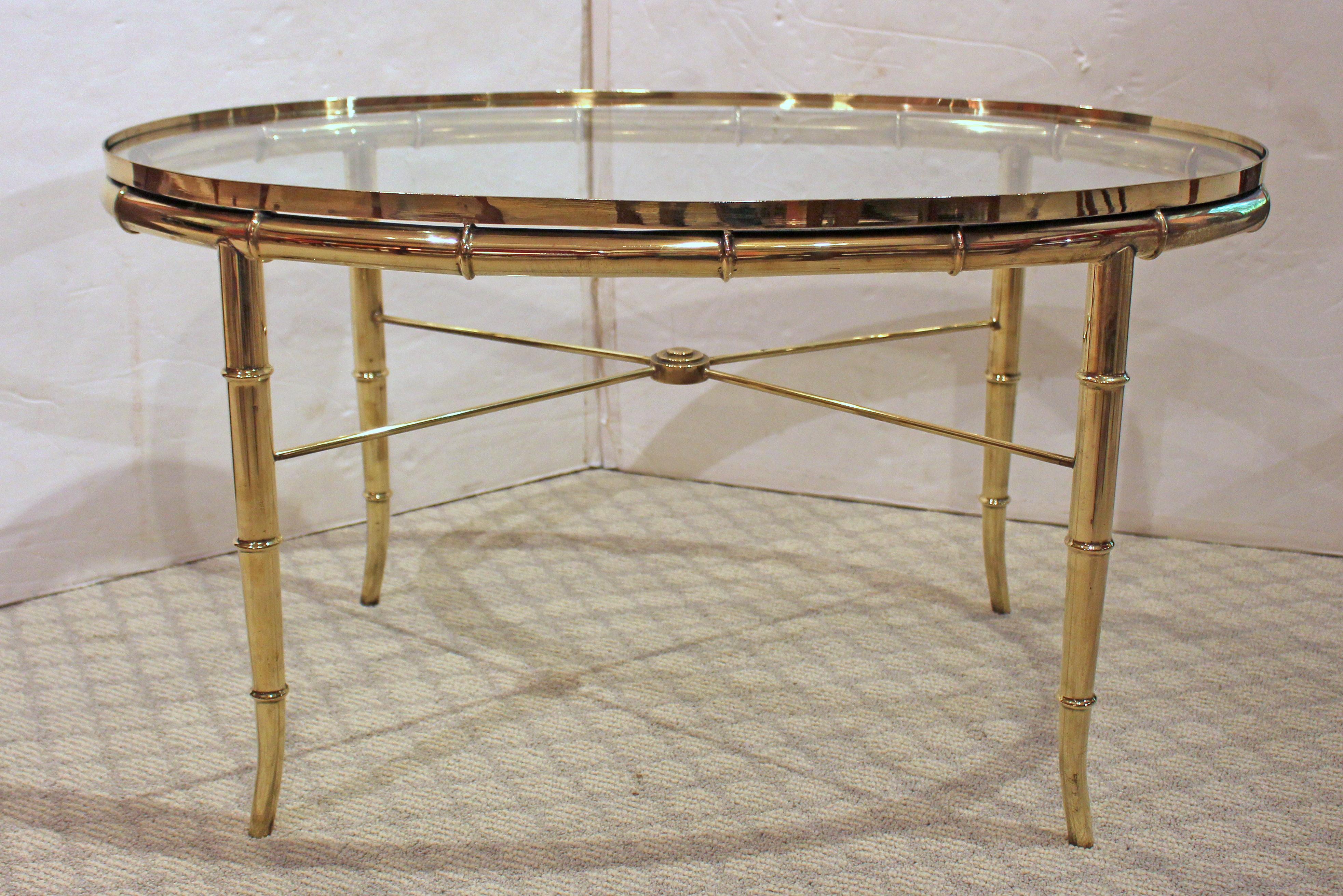 Circa 1970s oval brass & glass coffee table by Mastercraft, Grand Rapids, MI. Mid century modern. Elegant, tapered faux bamboo legs with medallion centered cross stretchers.

29.5