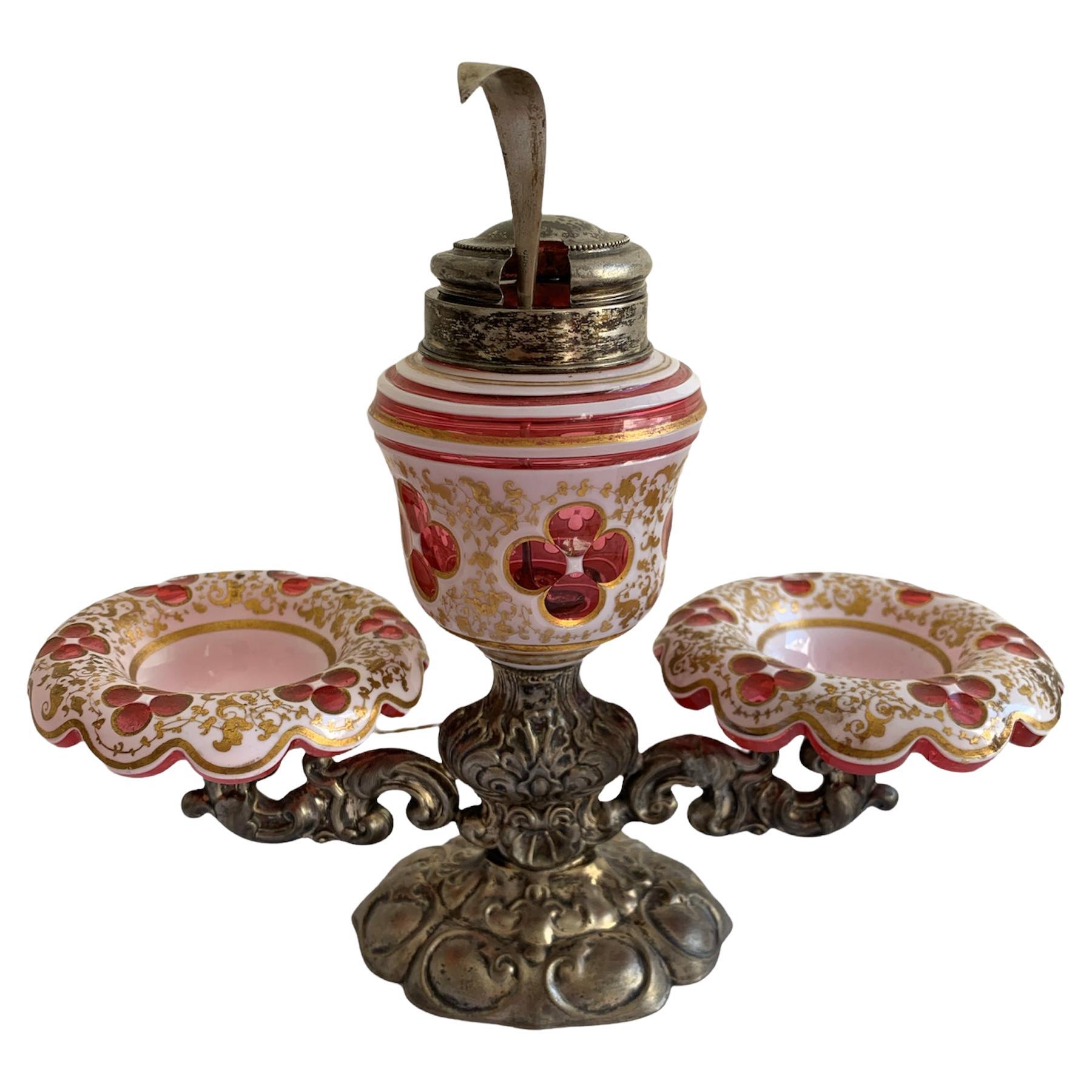 Antique glass and metal cruet set with 800-silver spoon, the silverplated engraved metal stand parts in two holders for two glass plates, the plates are in bohemian cranberry galss with white opaline glass overlay and fine gilding decoration,