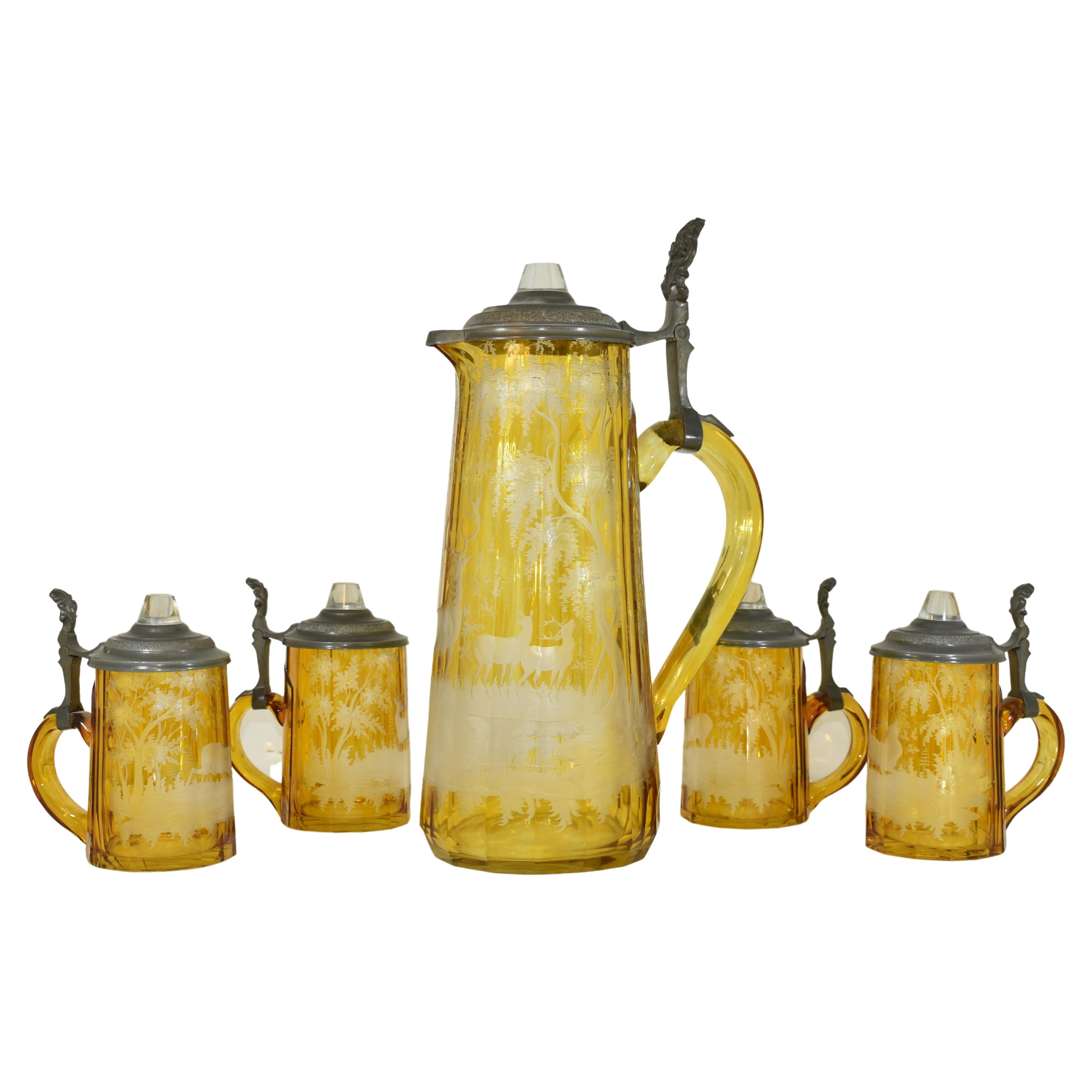 Set of a jug and four matching glasses, finely engraved all around with scenes of nature, the jug's polygonal body features a continuous forest scene with deer and stags among vegetation and massive, spreading trees, both glasses with further scenes