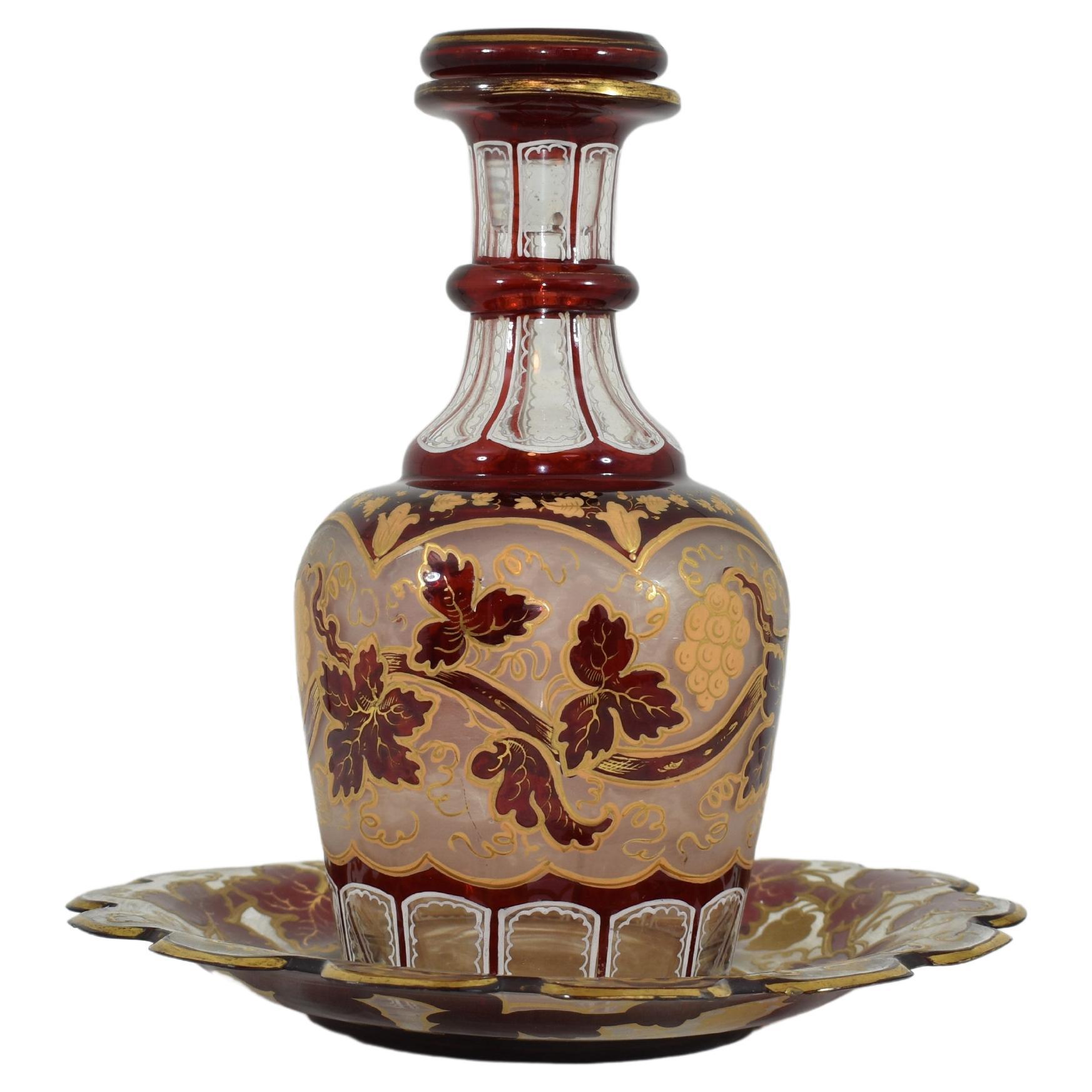 An exquisite bottle and stopper with matching plate made of ruby red and transparent blown glass, decorated all around with multiple shapes and patterns, white enamel decoration on the base and neck of the bottle, the circular body is profusely