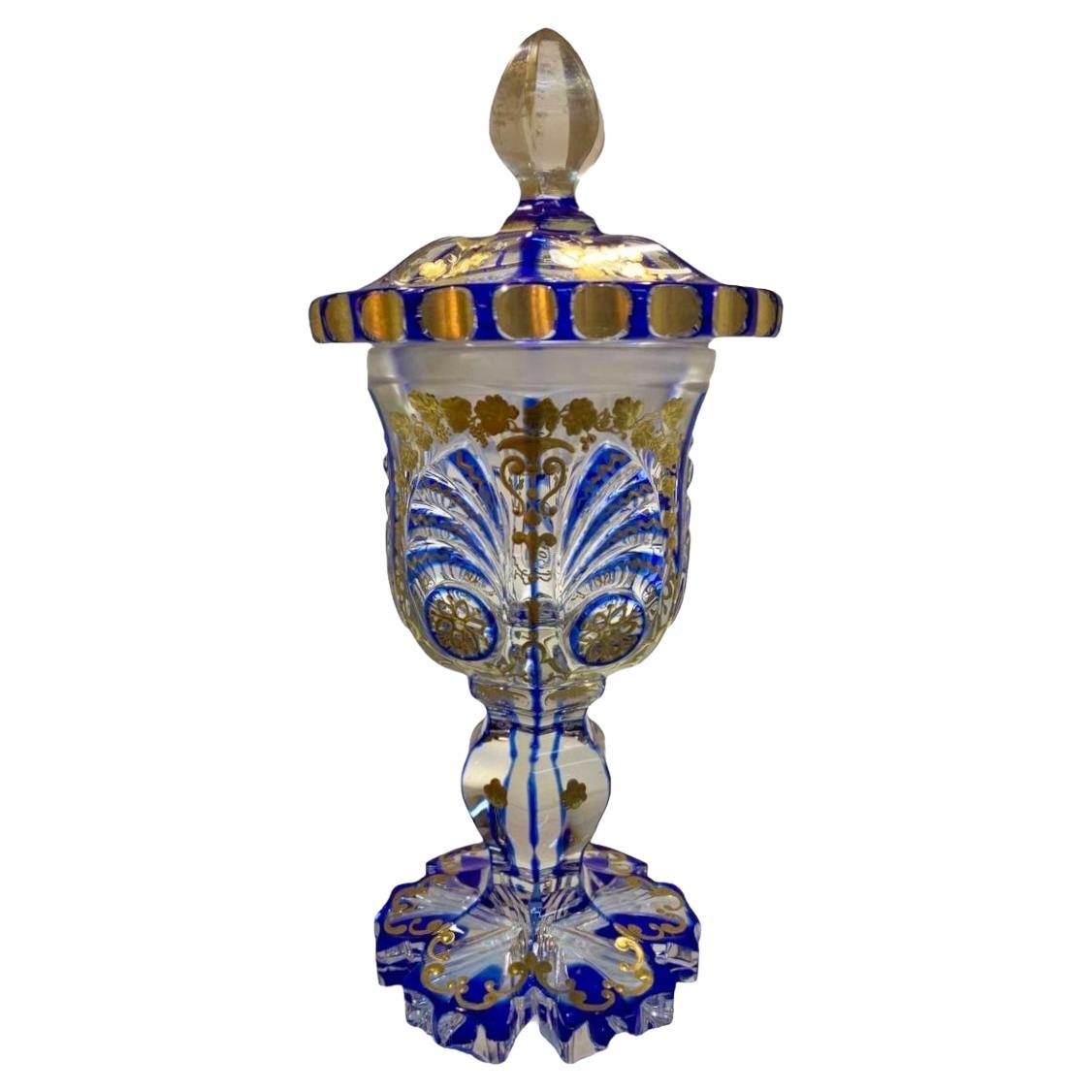 gobelet antique en verre superposé avec couvercle
Verre richement taillé dans des formes variées
abondamment décorée tout autour de fleurs et de rinceaux en émail doré
repose sur un pied festonné avec une base évasée en bas

Bohemia, 19ème