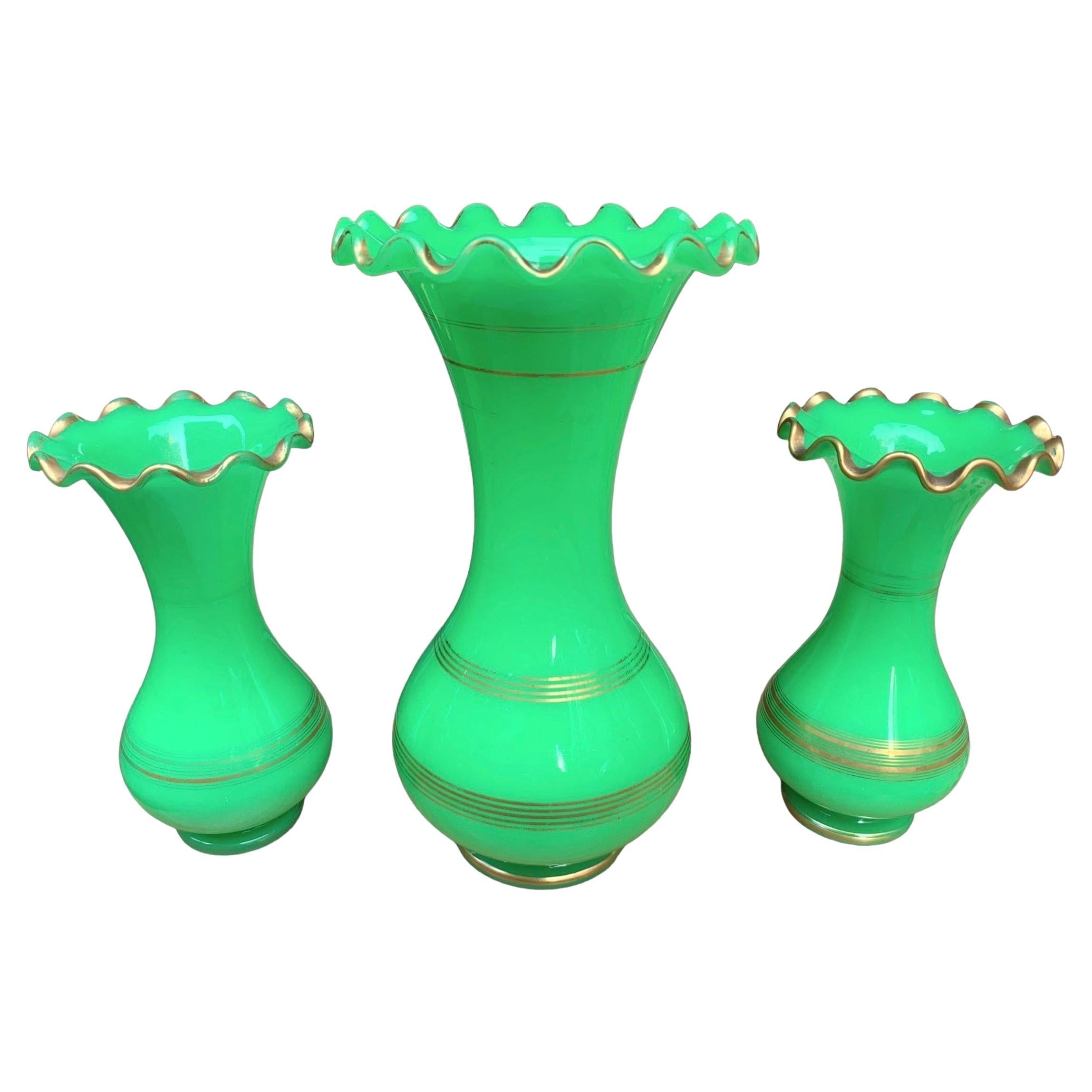 A set of 3 matching opaline glass vases

Beautiful green color with gilding highlights decoration and wavy scalloped rims

France, 19th Century

Measures: Large Vase stands 35 cm high
Small Vases 25 cm high.