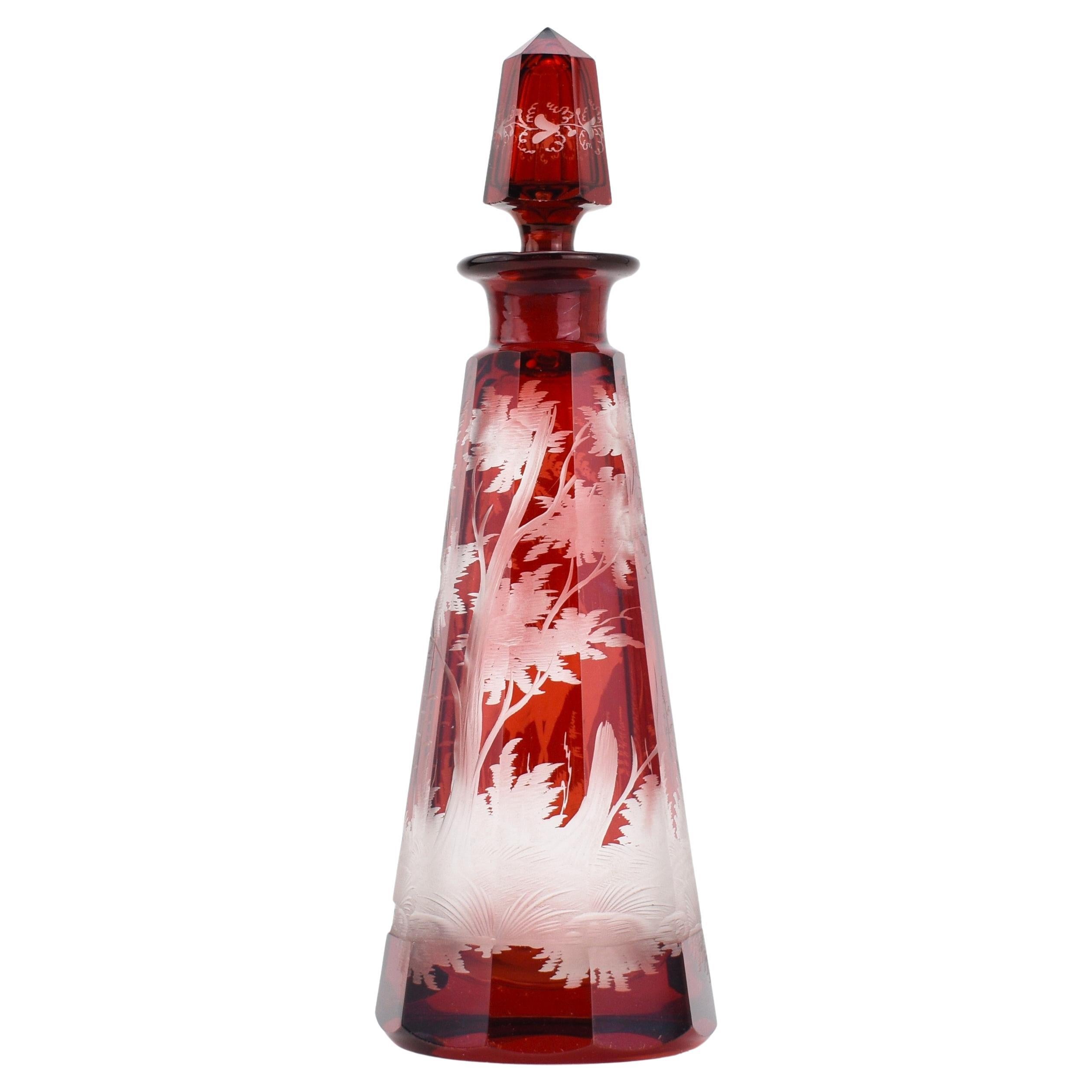 Ce rare flacon de parfum rouge rubis, fabriqué en verre taillé de Bohême de haute qualité, est un exemple remarquable de l'art du verre de Bohême du XIXe siècle. Le corps est découpé en plusieurs panneaux latéraux. Le clou de la pièce est sa scène
