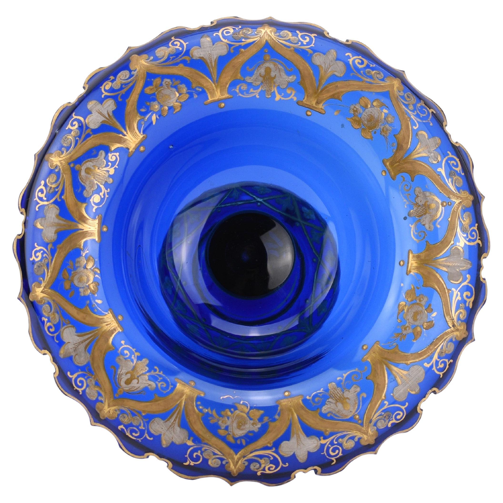 Centre de table en verre bleu cobalt avec décoration en émail doré - Bohemia, 19e siècle

Cette élégante coupe tazza, fabriquée en verre bleu cobalt, illustre la qualité de la verrerie bohémienne du XIXe siècle. Le corps circulaire est orné