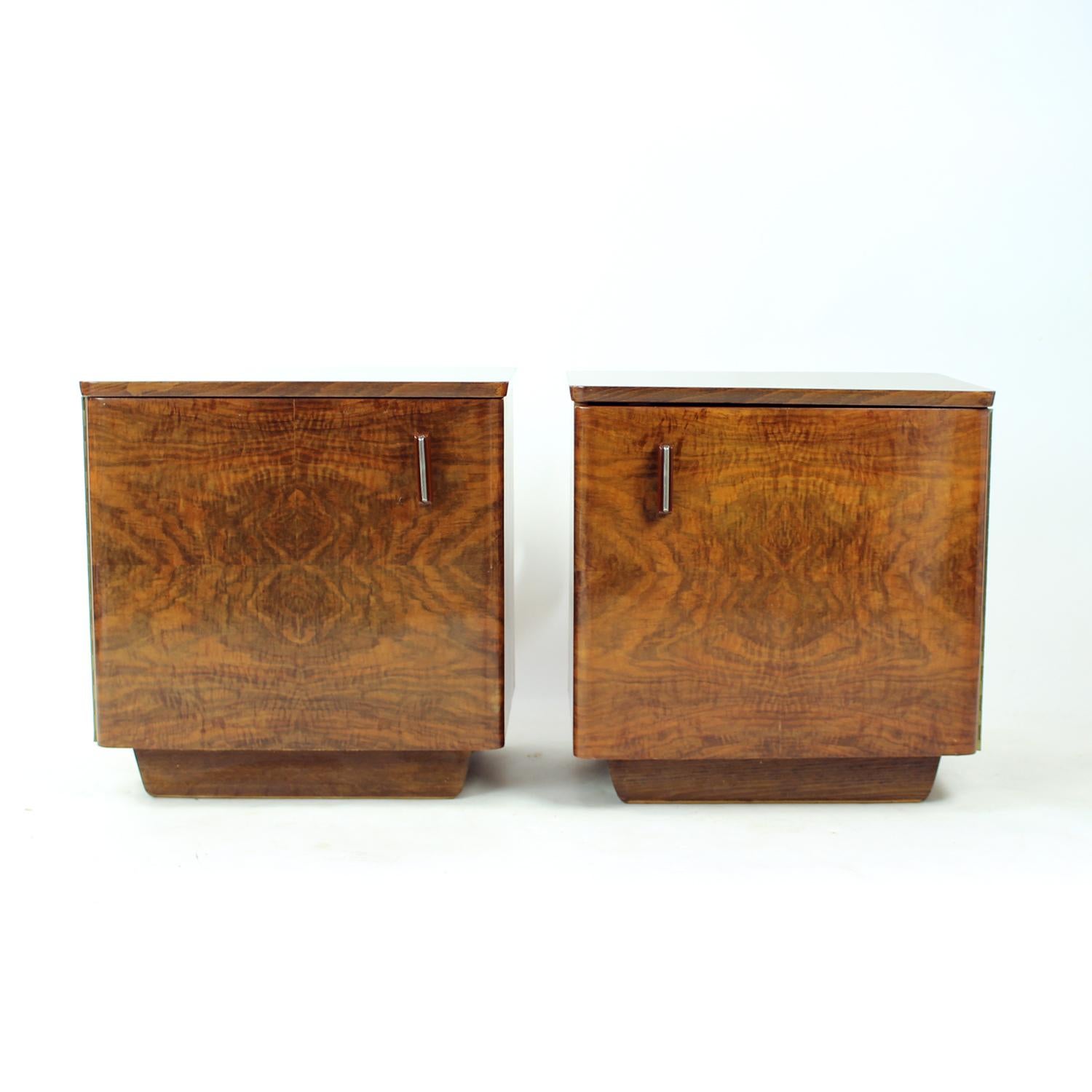 Une magnifique paire de tables de chevet vintage des années 1960, fabriquée avec un placage de noyer exquis et finie avec un plateau et une porte avant en gomme-laque très brillante. Les tables semblent carrées au premier coup d'œil mais présentent