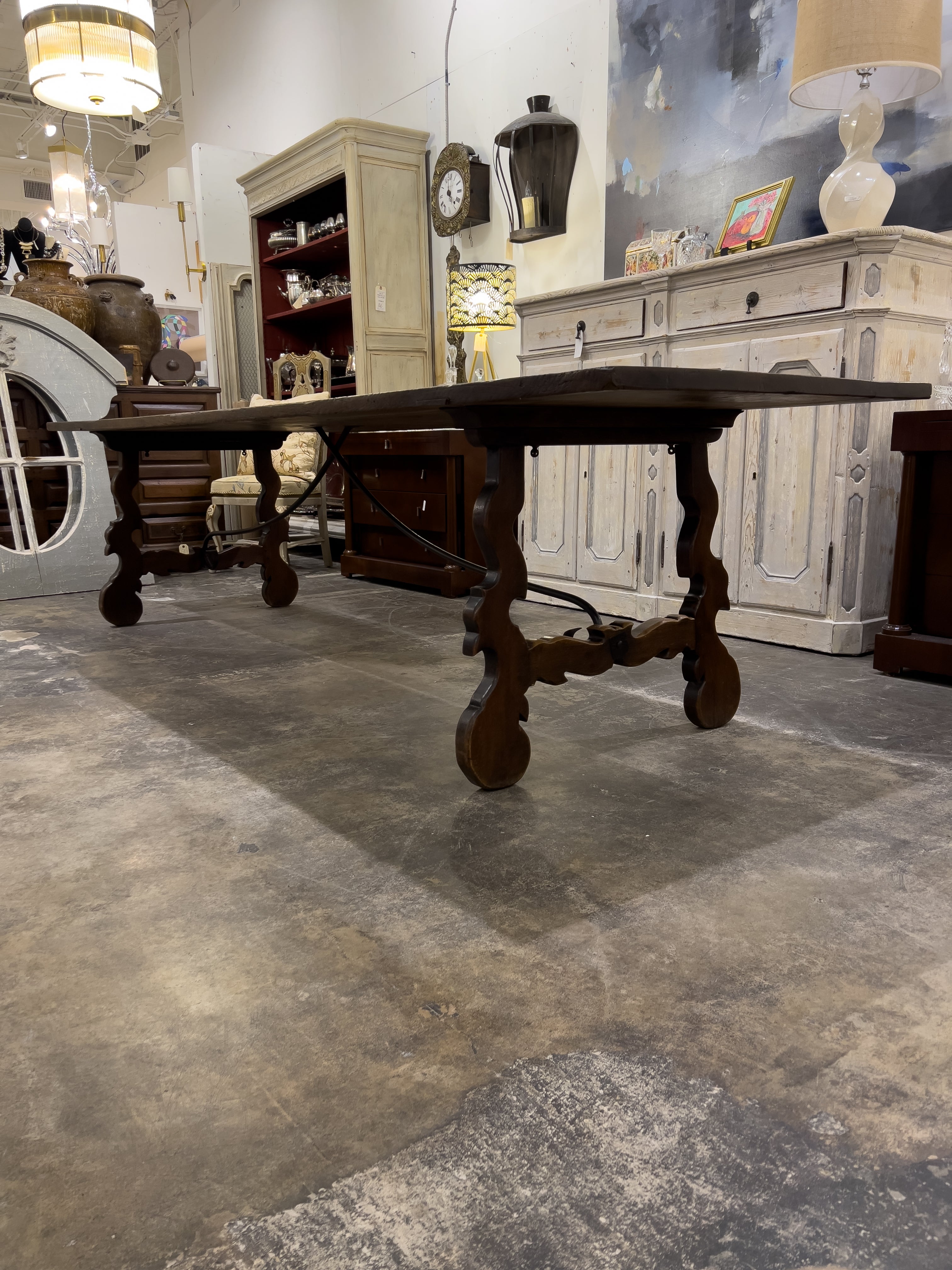 19th century Spanish trestle table with a shaped iron trestle and beautifully carved legs. The rectangular trestle table stands on two carved scrolled legs joined together with a forged metal stretcher. The elegant table is in good condition