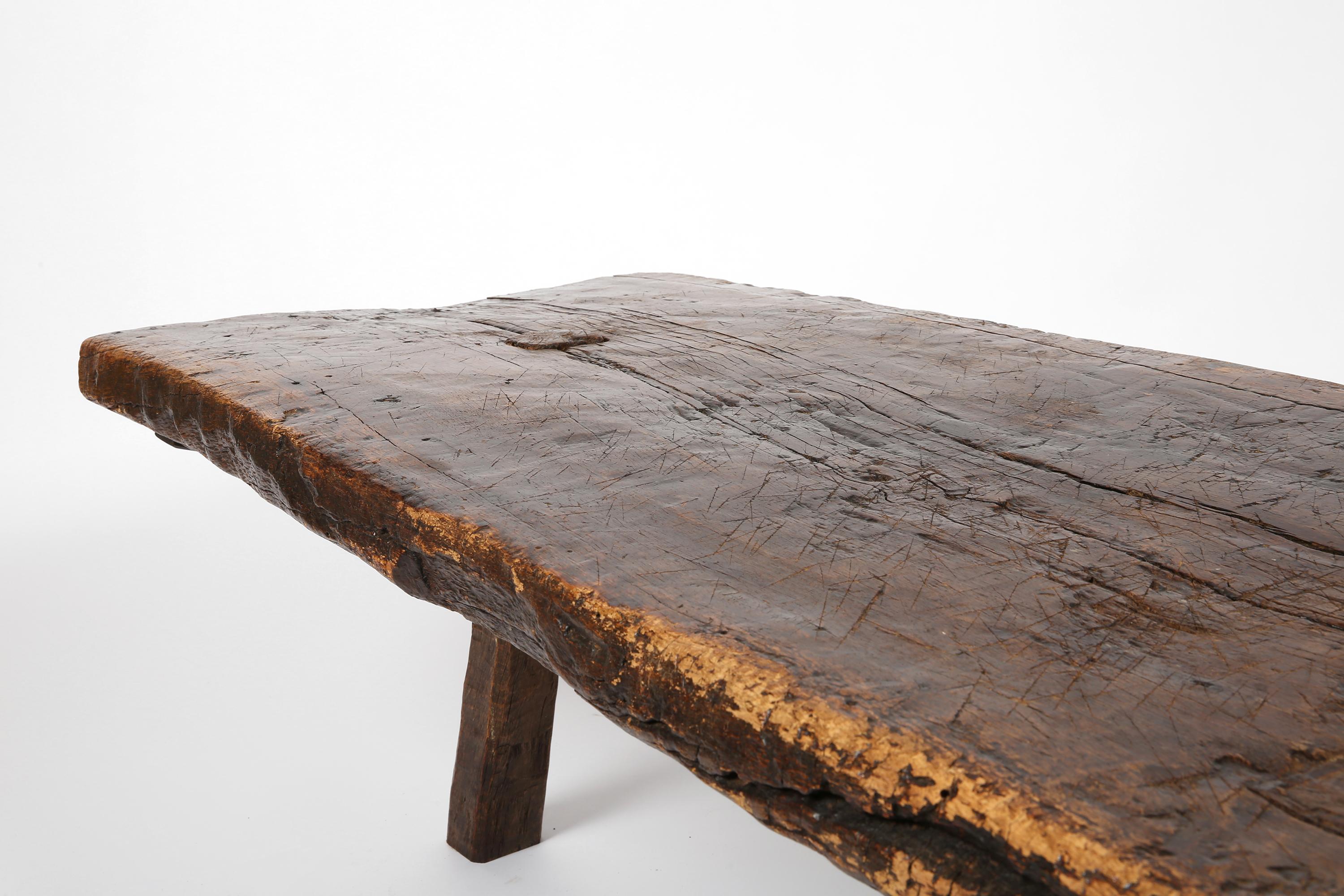 Grande table de berger du début du XVIIIe siècle, construite de manière primitive à partir d'une seule et importante planche de bois - probablement du noyer ou du chêne - et dotée de trois pieds simplement taillés. Richement patinée et portant les