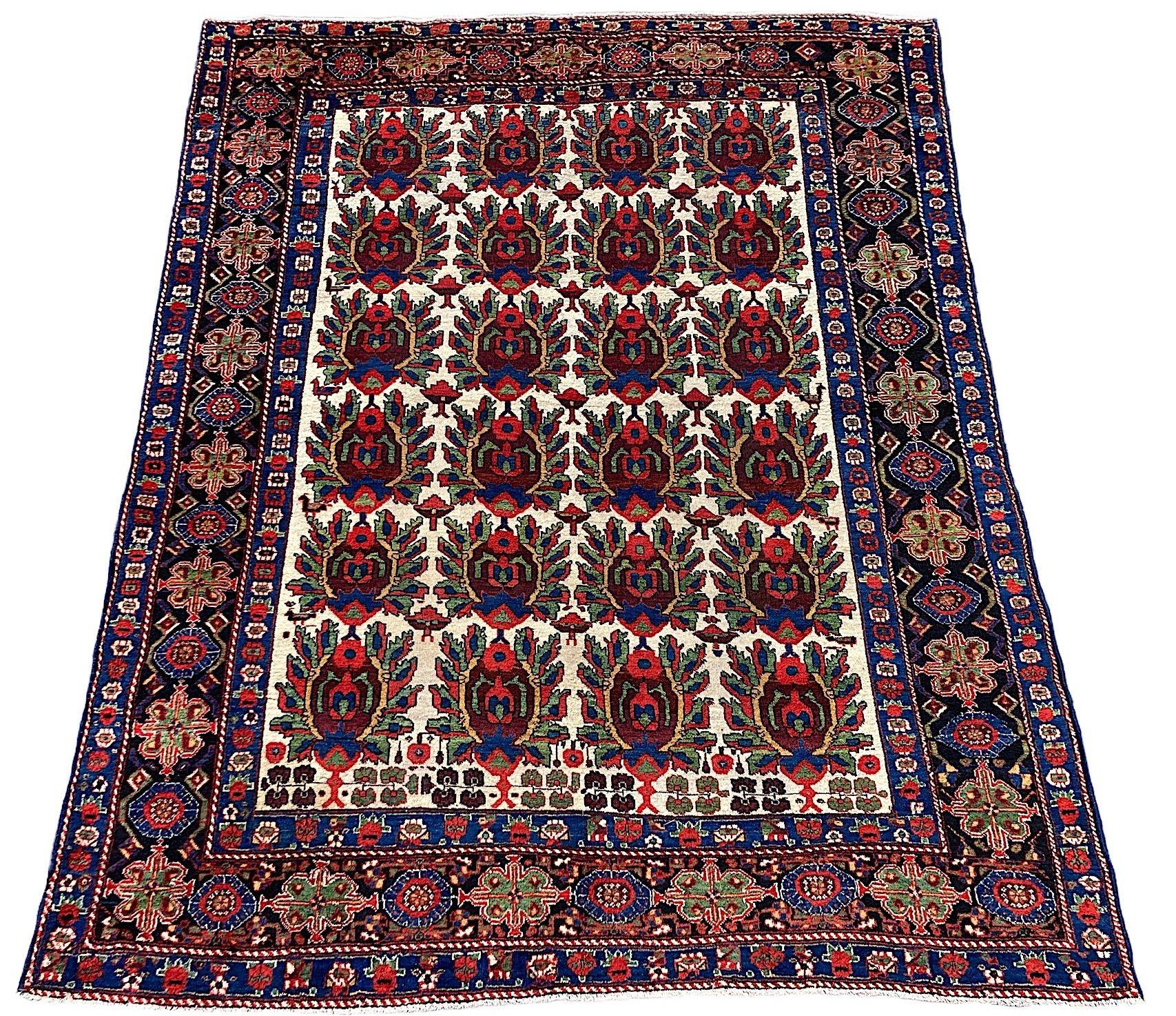 Un favoloso tappeto Afshar antico, tessuto a mano nel 1900 circa. Il tappeto presenta un disegno a scudo ripetuto all over su un insolito campo avorio circondato da un bordo indaco profondo. Tessuto finemente con lana morbida e vellutata e colori
