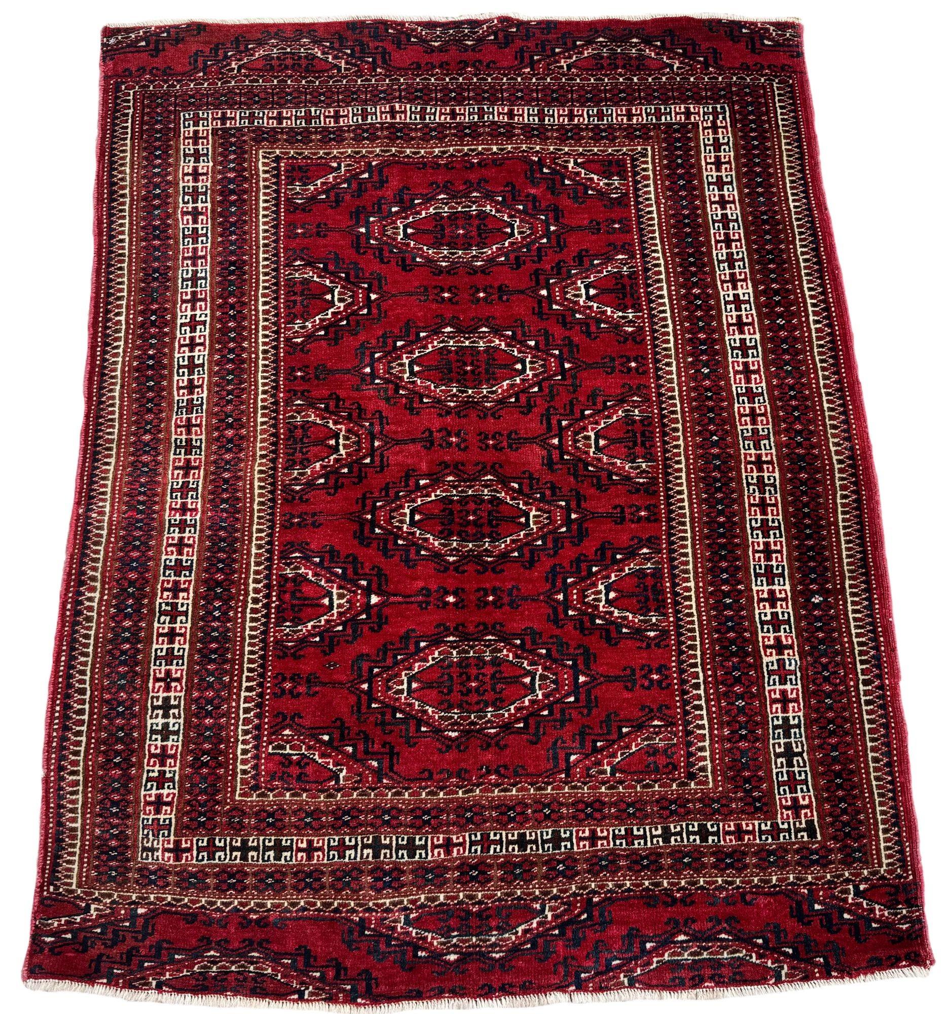 Un delizioso tappeto Yomut vintage, tessuto in Turkmenistan a metà del XX secolo. Il tappeto presenta un tradizionale disegno a gul all over su un campo rosso intenso e ottimi colori secondari. Tessuto finemente con lana di ottima